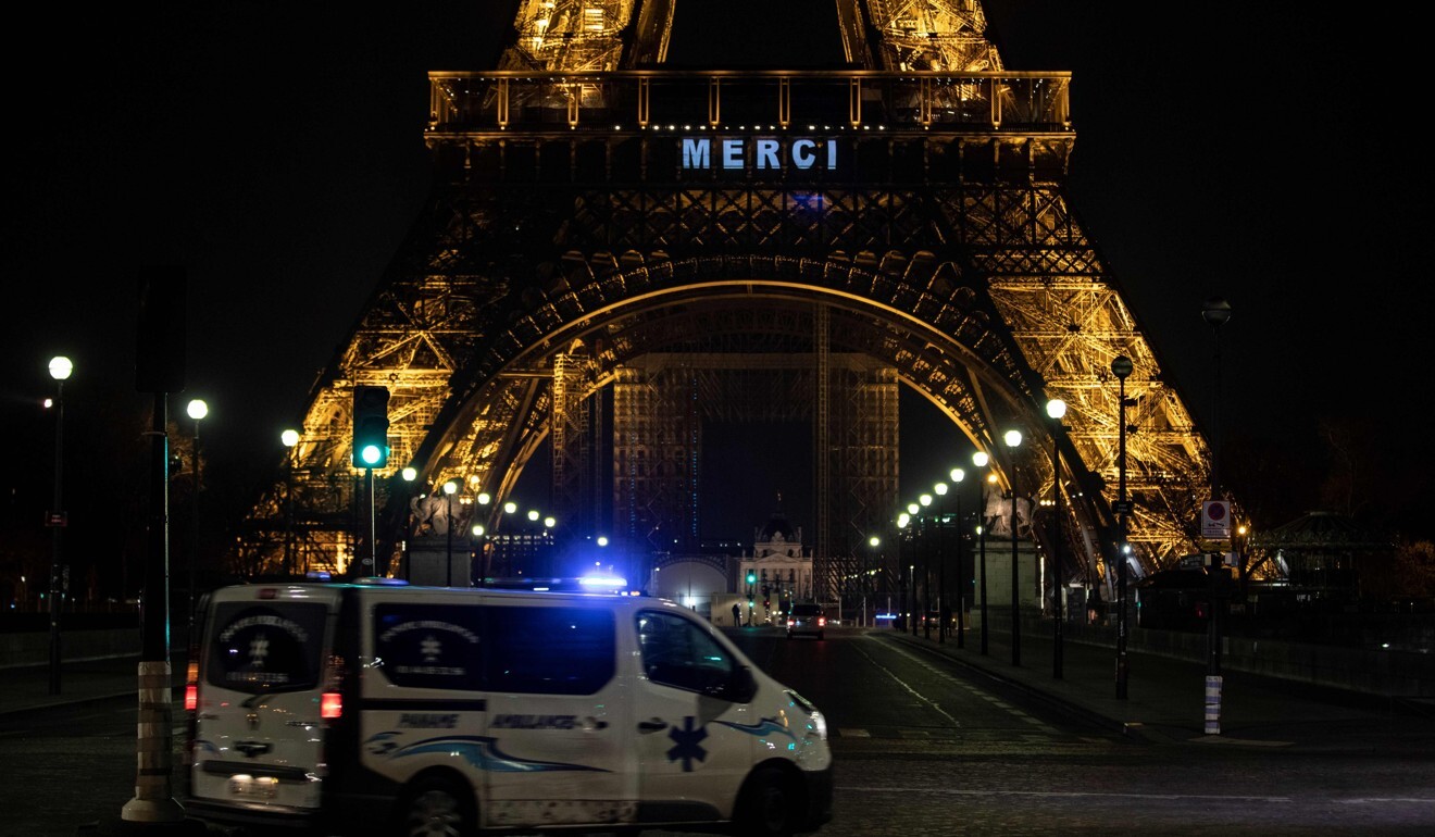 An ambulance passes near the Eiffel Tower, on which the word “merci” (“thank you” in French) is displayed in tribute to health care workers, security personnel and workers mobilised during a lockdown in France. Photo: AFP