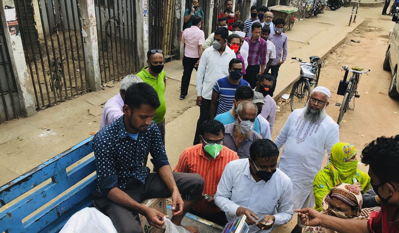 People, some wearing face masks, line up to shop for essential items from a roadside truck in Dhaka last Wednesday. Photo: AP