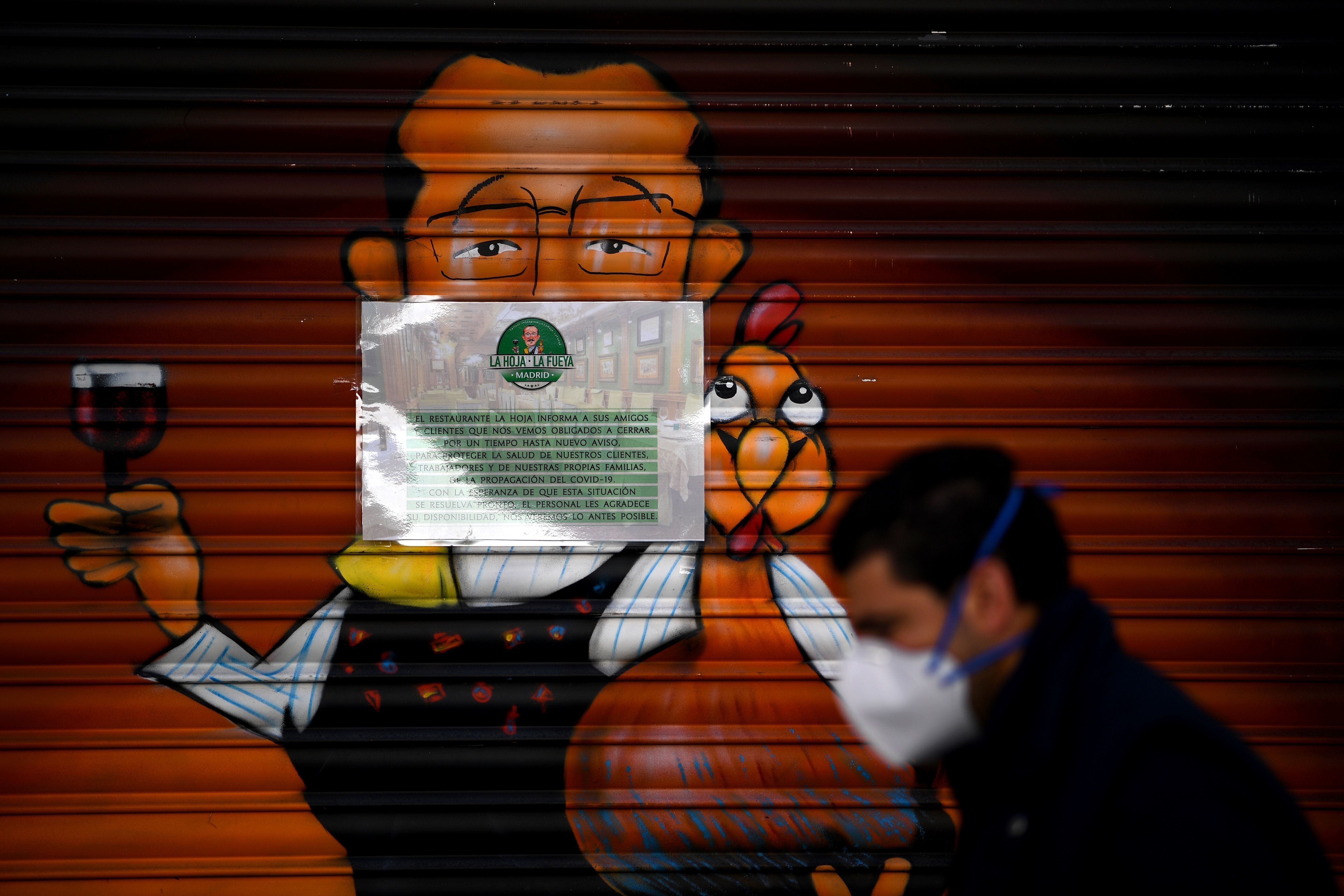 A man wearing a face mask walks past a closed restaurant in Madrid amid a national lockdown to fight the spread of Covid-19. Photo: AFP