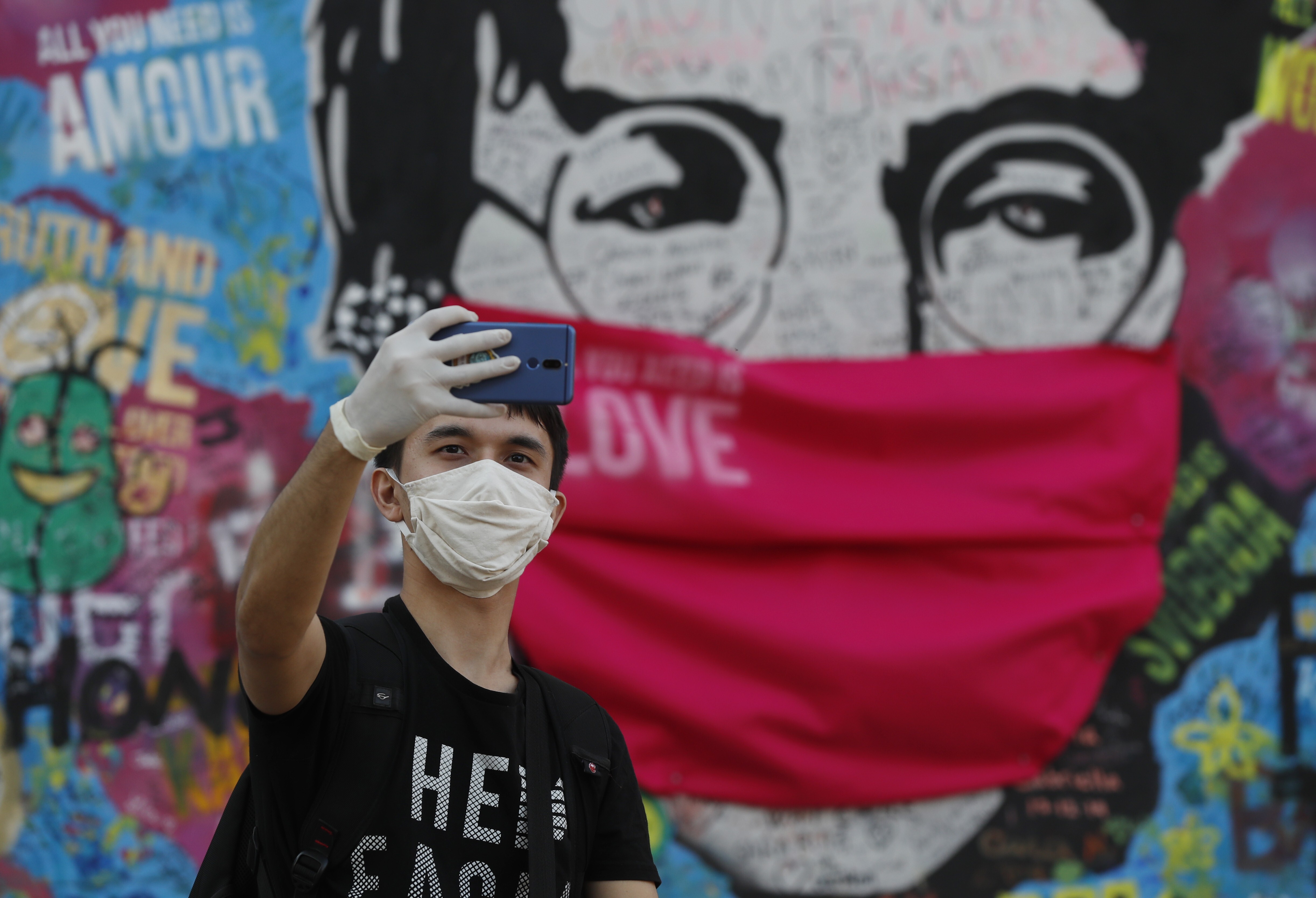 The ‘Lennon Wall’ with a face mask attached in Prague. The Czech government said Monday it would ease its tough anti-virus measures ahead of Easter. Photo: AP