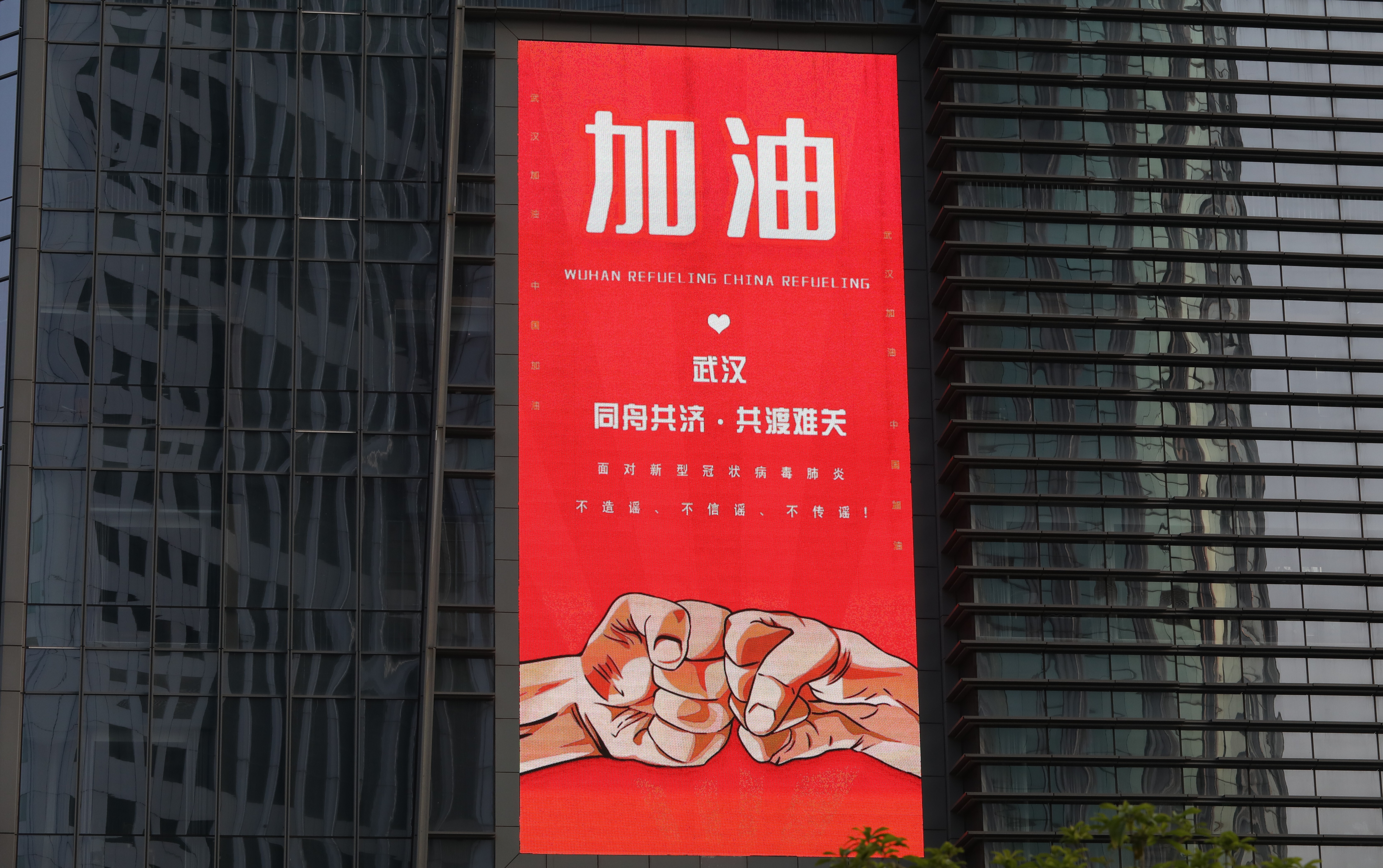 A big screen on a building says: Fight On Wuhan, a day before the city reopened on April 8. China is emerging from lockdown ahead of other countries. Photo: Simon Song