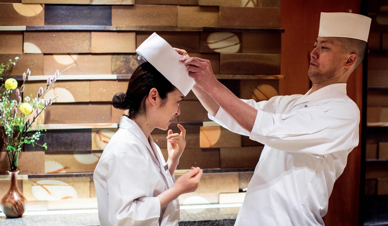 Head chef Akifumi Sakagami, right, adjusts the hat of apprentice Mizuho Iwai. Photo: AFP