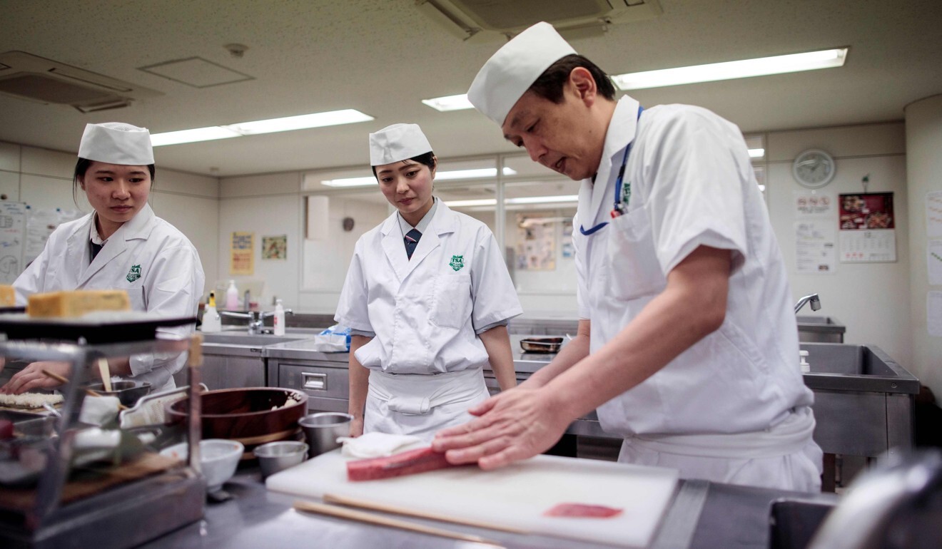 Fumimasa Murakami, right, shows how to cut fish at Tokyo Sushi Academy. Photo: AFP