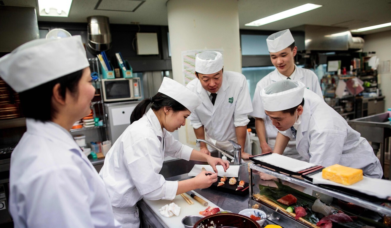 Fumimasa Murakami, centre, a teacher at Tokyo Sushi Academy, watches his students decorating a sushi set. Photo: AFP