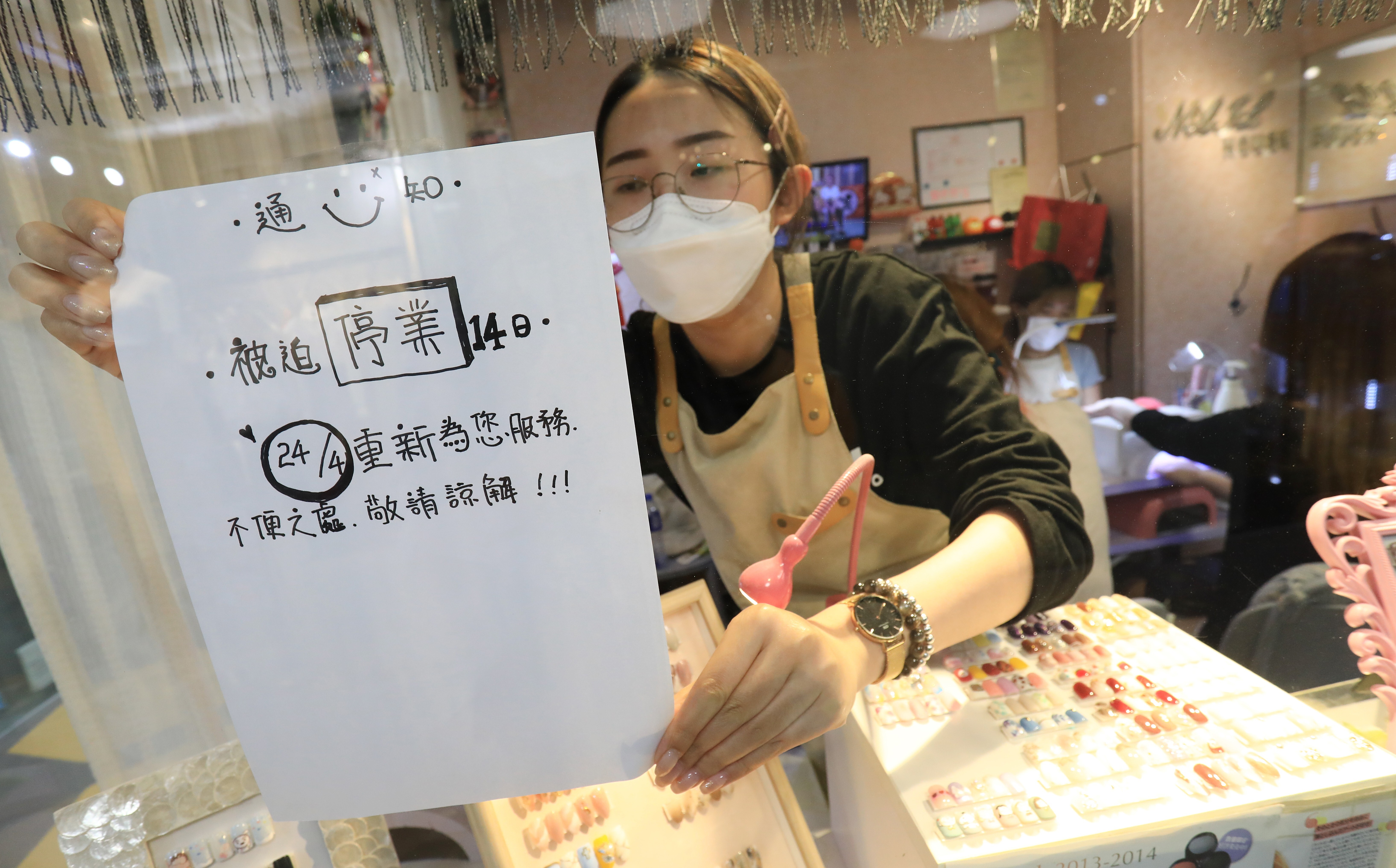 Tang Tze-ching puts up a sign saying the nail salon she works at in New Town Mall, Mong Kok, will be closed for 14 days because of government rules designed to slow the spread of the coronavirus. Photo: May Tse