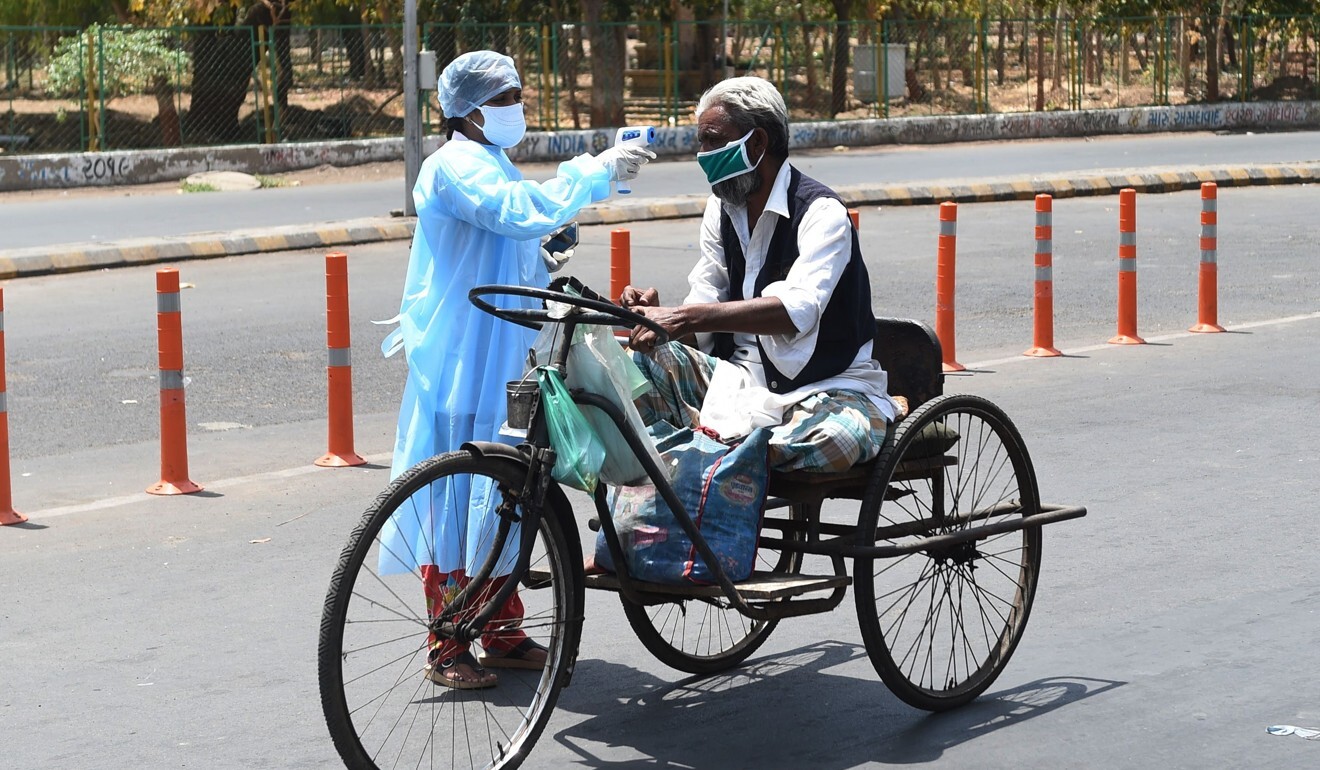 A health worker checks the body temperature of a man with mobility impairment in Ahmedabad on Wednesday. Photo: AFP