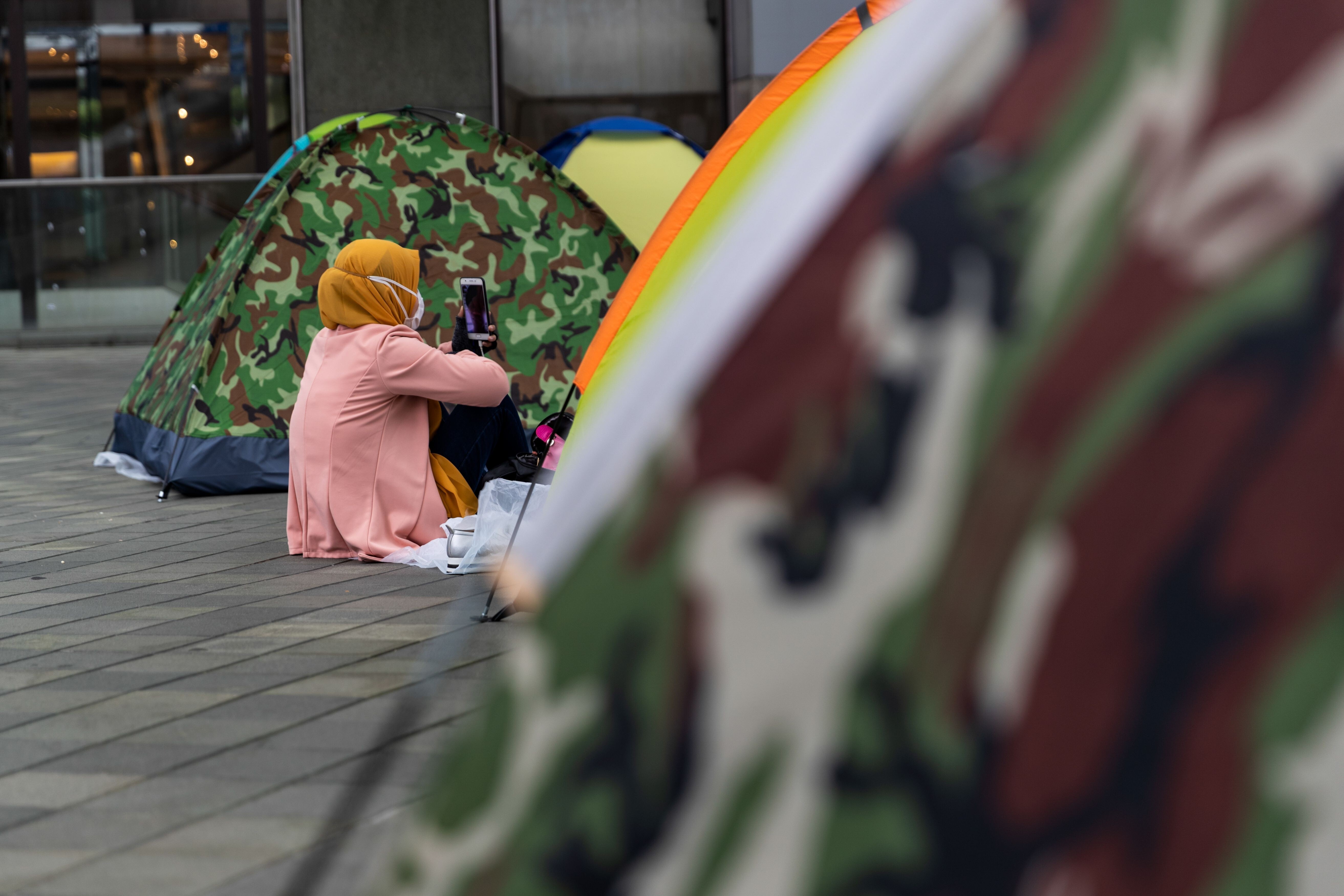 A domestic helper wearing a face mask spends time with other workers on their day off in Hong Kong on April 5. In an economic downturn, many domestic workers may lose their job simply because their employers can no longer afford to pay for domestic help. Photo: AFP