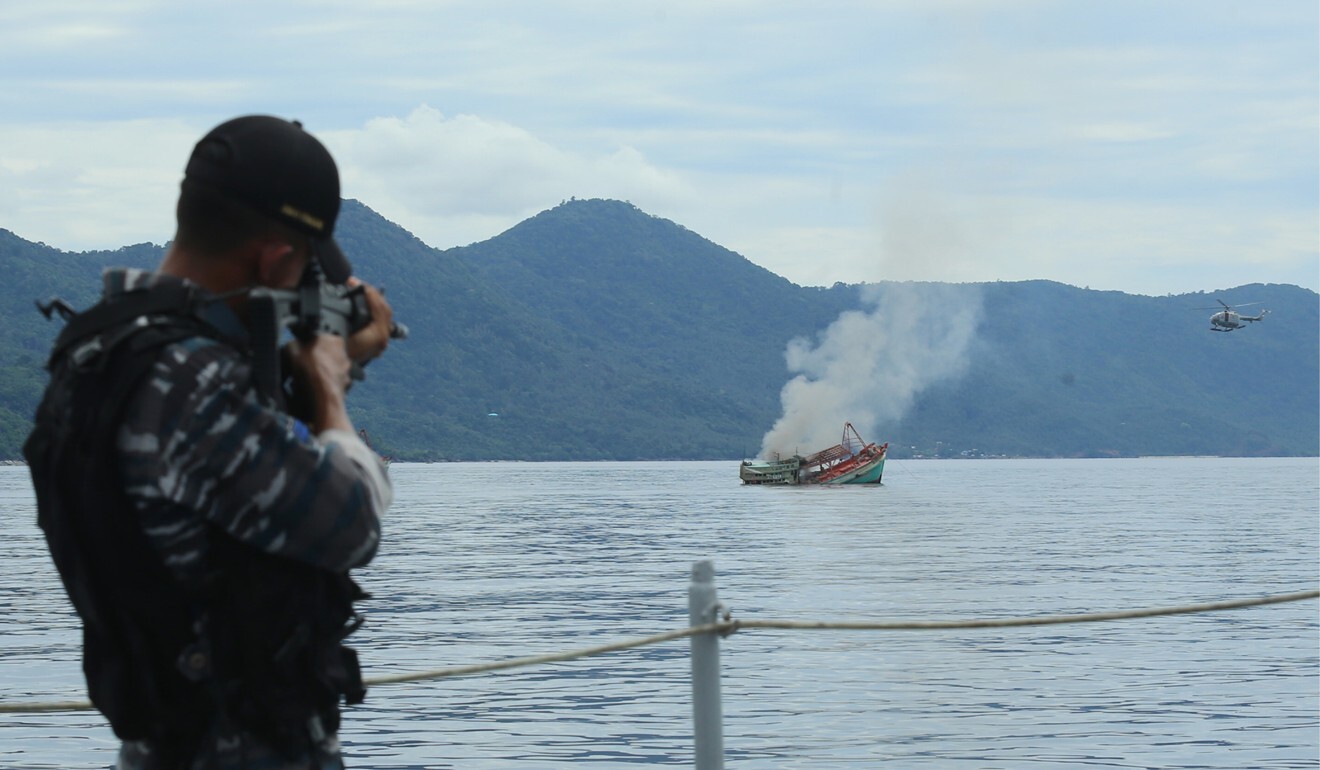 An Indonesian Navy officer takes aim at a Vietnamese fishing boat detained due to illegal fishing in Riau waters in December 2014. Indonesia blew up and sank three empty Vietnamese boats on December 5, its navy said. Photo: AFP