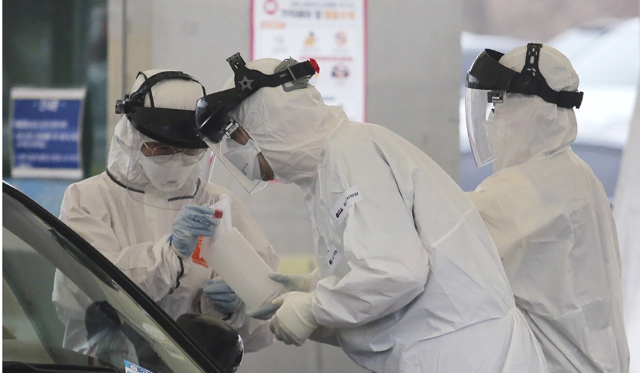 Medical staff wearing protective suits take samples from a person with suspected coronavirus symptoms in South Korea. Photo: AP