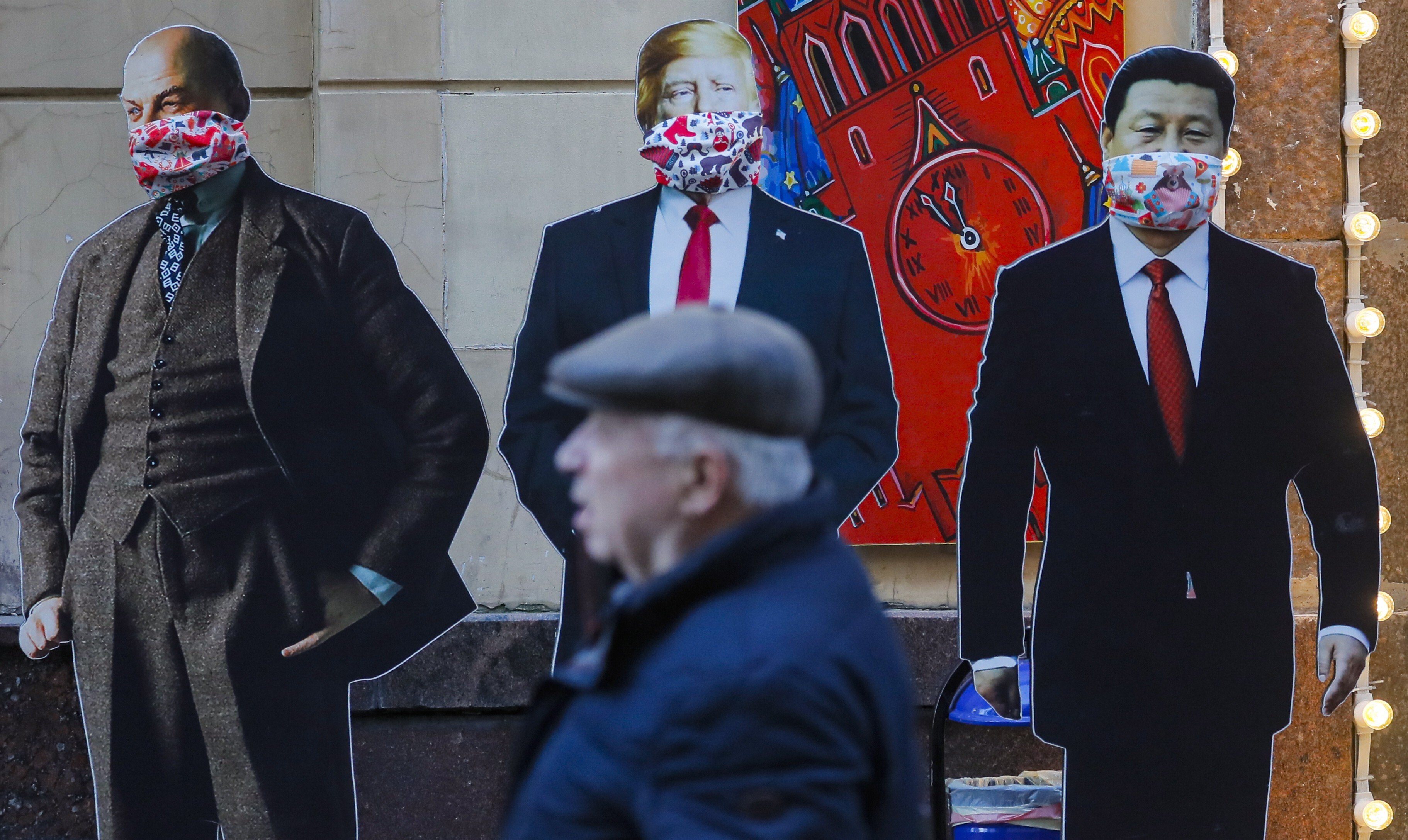 A man passes cardboard figures of Soviet Union founder Vladimir Lenin, US President Donald Trump and Chinese President Xi Jinping wearing face masks near a souvenir shop in Moscow. The three countries will be instrumental in shaping the post-coronavirus world. Photo: EPA-EFE