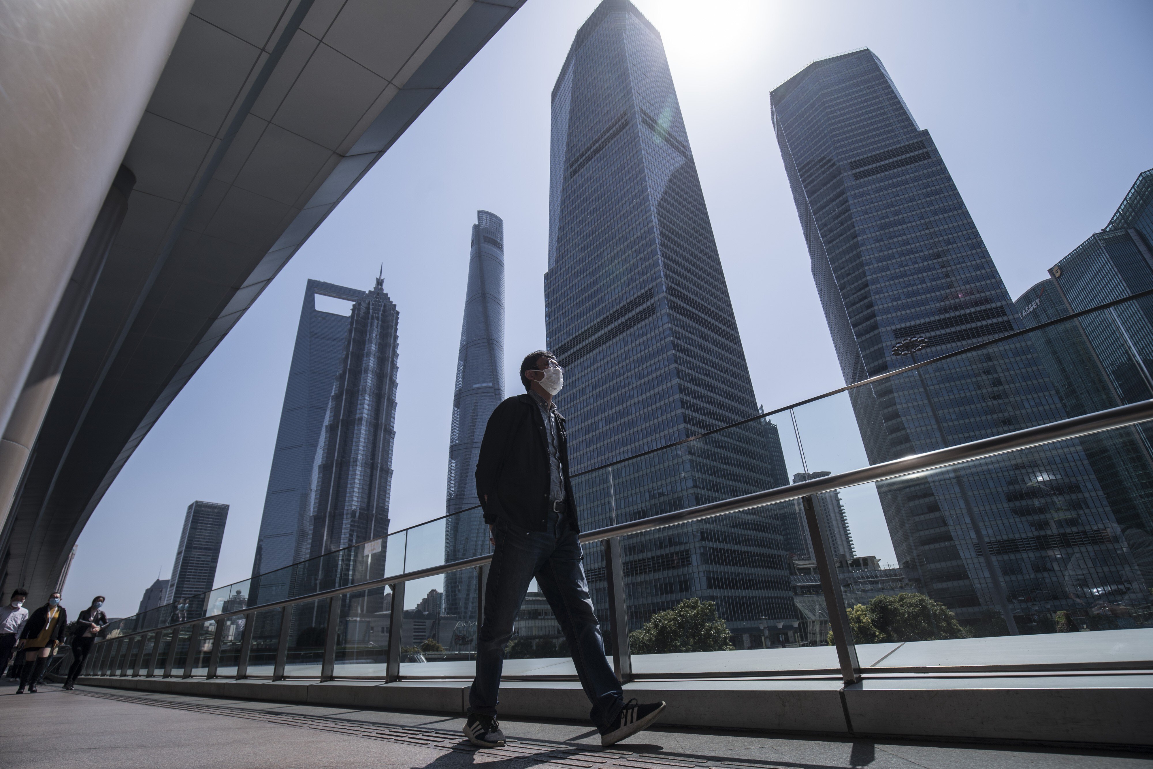A man wearing a protective mask walks through the Lujiazui financial district in Shanghai. Most of China is now considered low-risk and should return to normal work and life, Premier Li Keqiang said. Photo: Bloomberg