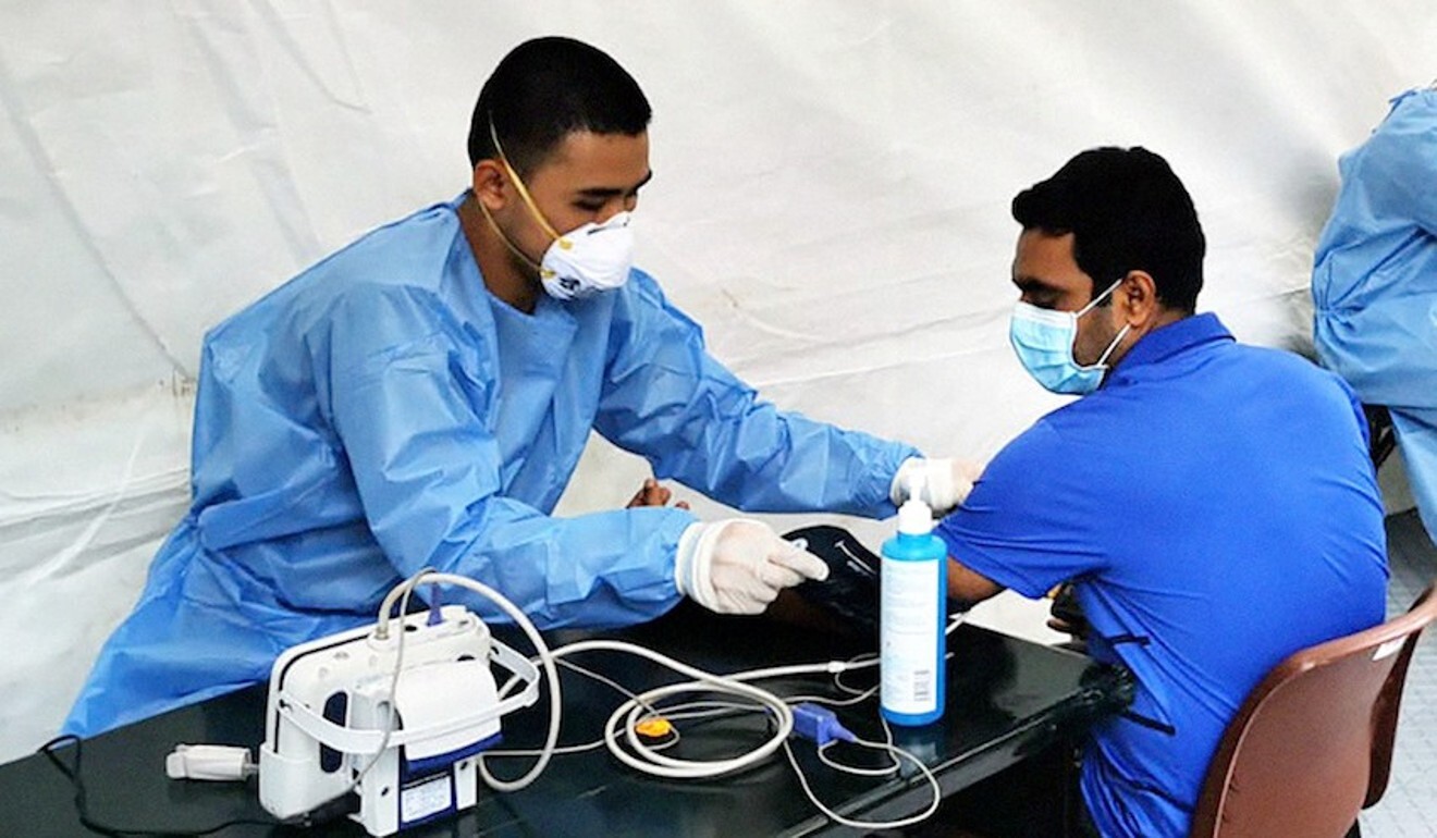 A migrant worker is attended to by personnel from Singapore’s Academy of Medicine. Photo: Reuters