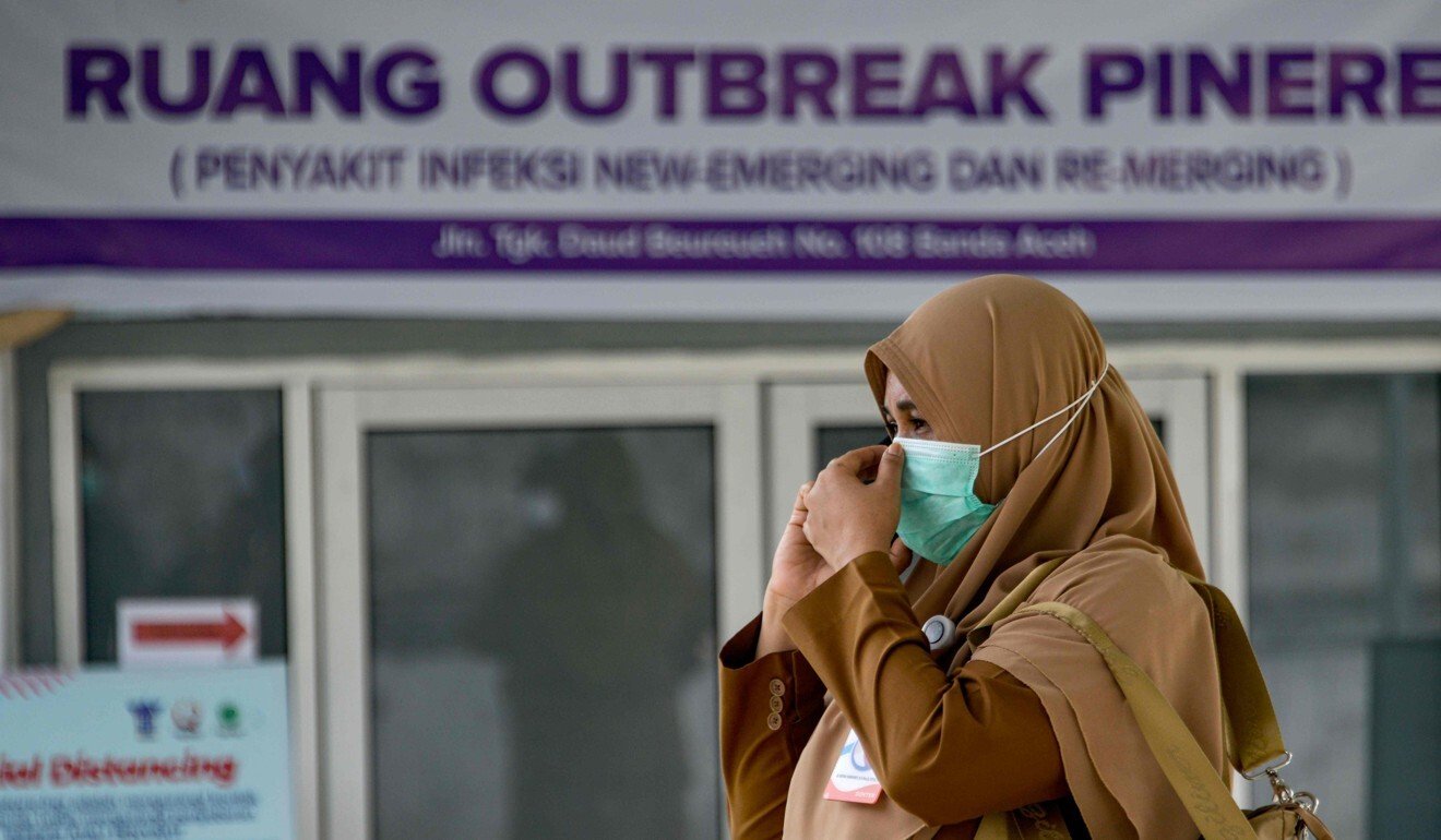 An Indonesian health official adjusts her face mask outside a quarantine facility on Monday. Photo: AFP