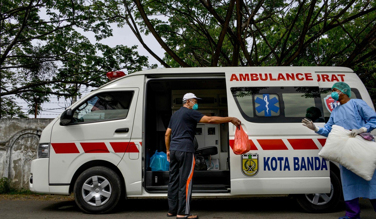 A recovered coronavirus patient gestures to a medical worker before boarding an ambulance in Indonesia’s Banda Aceh. Photo: AFP