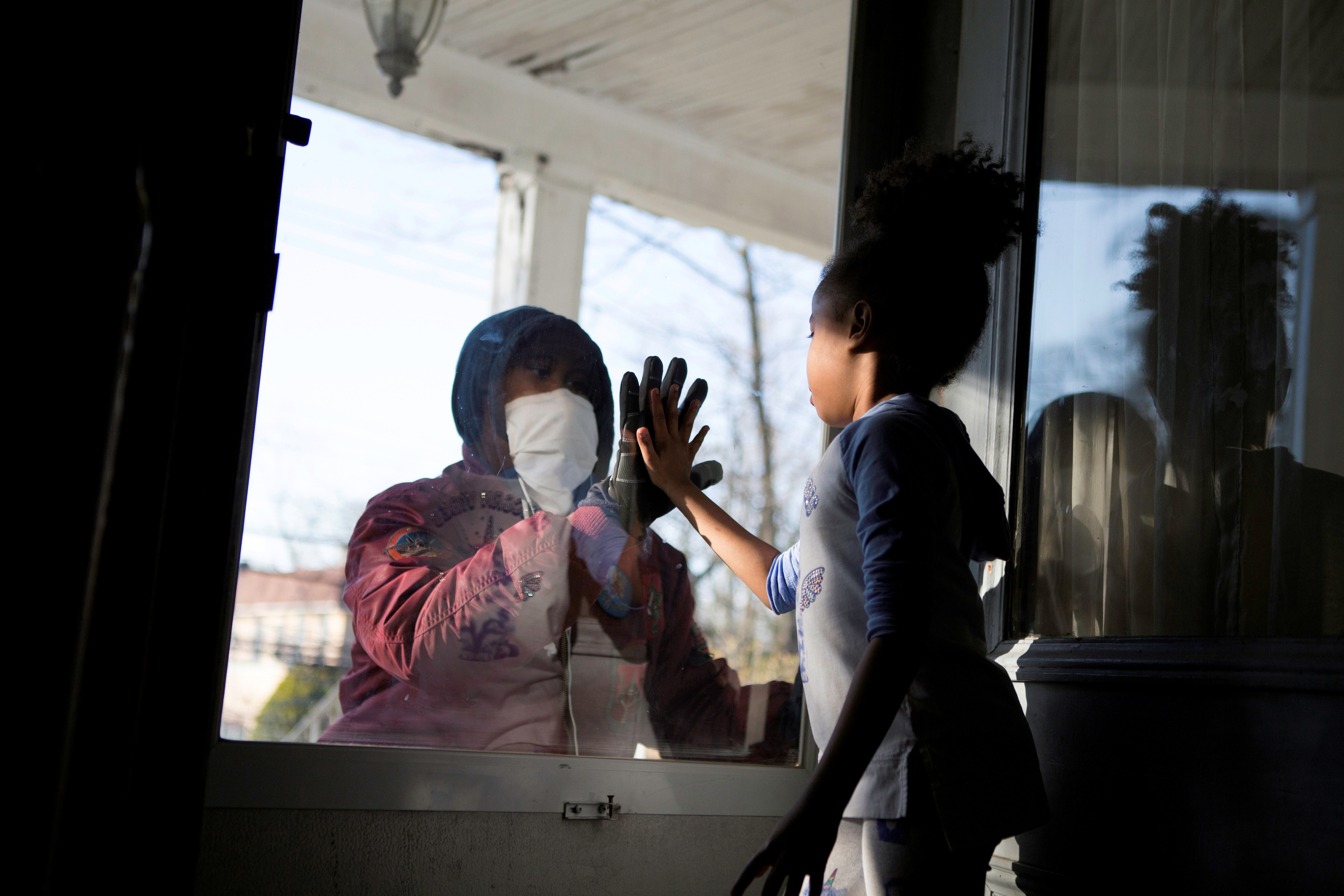 Hashim, an essential worker in the healthcare industry, greets his daughter through the closed door as he maintains social distance from his family as he works amid the coronavirus outbreak in New Rochelle, New Jersey. Photo: Reuters