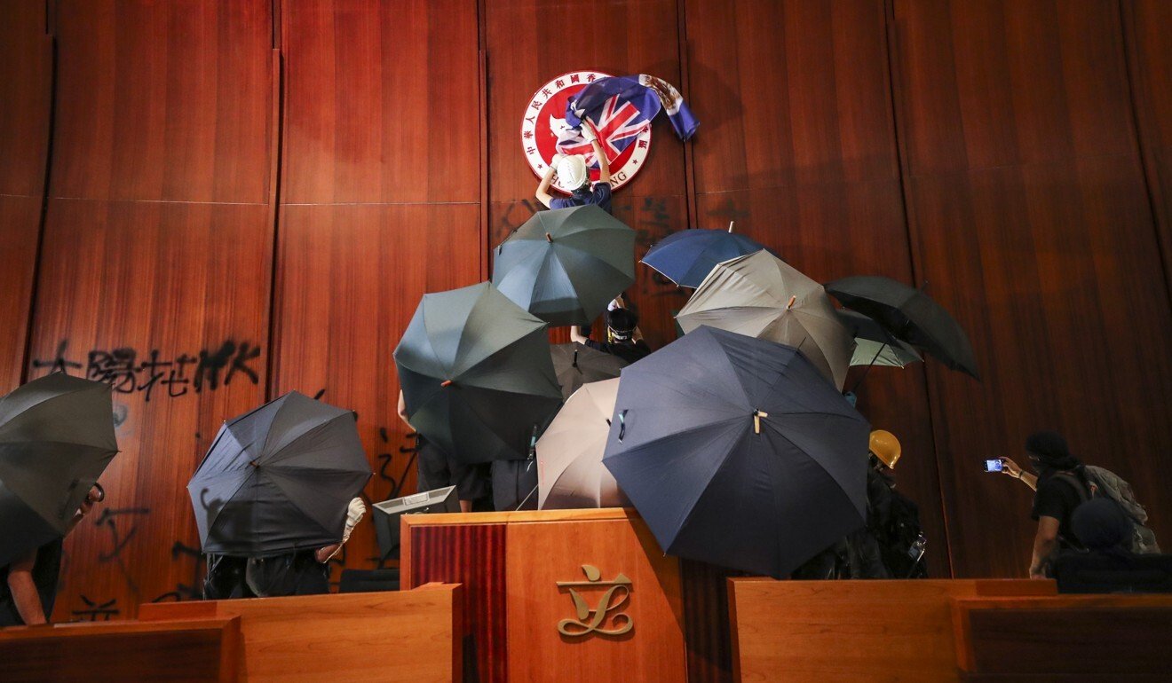 A protester covers the Hong Kong emblem with a British colonial flag after storming the Legislative Council chamber on the 22nd anniversary of Hong Kong's handover from Britain to China. Photo: Sam Tsang