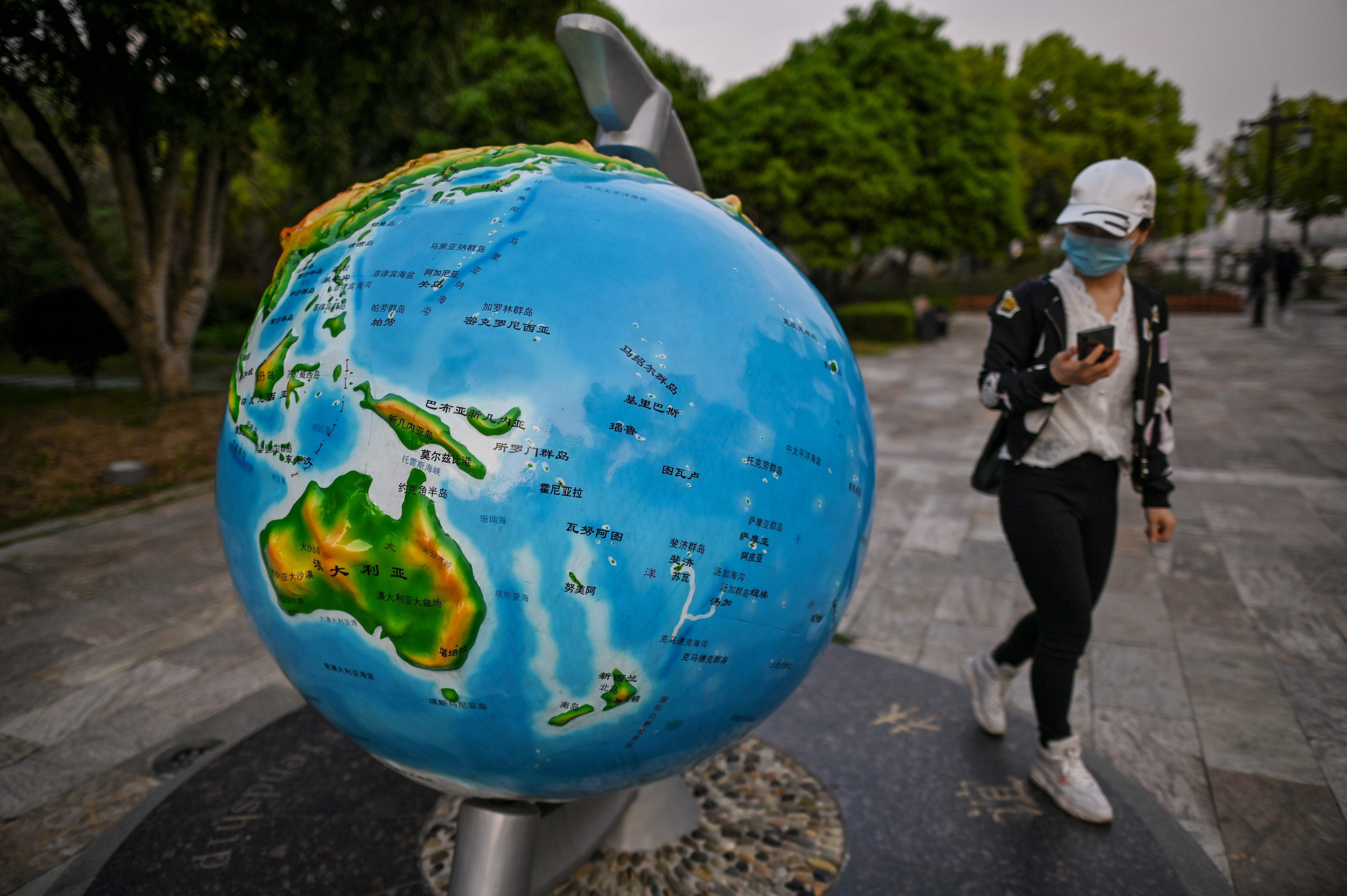 A woman wearing a face mask looks at a globe in a park in Wuhan, Hubei province, on April 8. China’s pandemic diplomacy should now focus on humanitarian efforts, rather than a clumsy, self-righteous global political campaign. Photo: AFP
