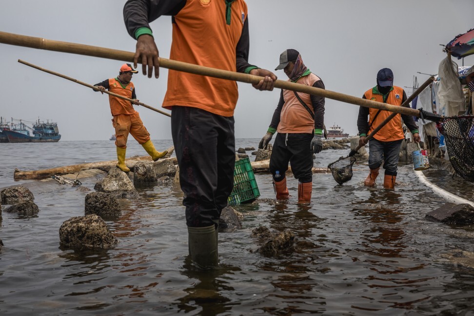 Workers from Jakarta’s environmental department rid a river of plastics and other waste. Photo: Jonas Gratzer