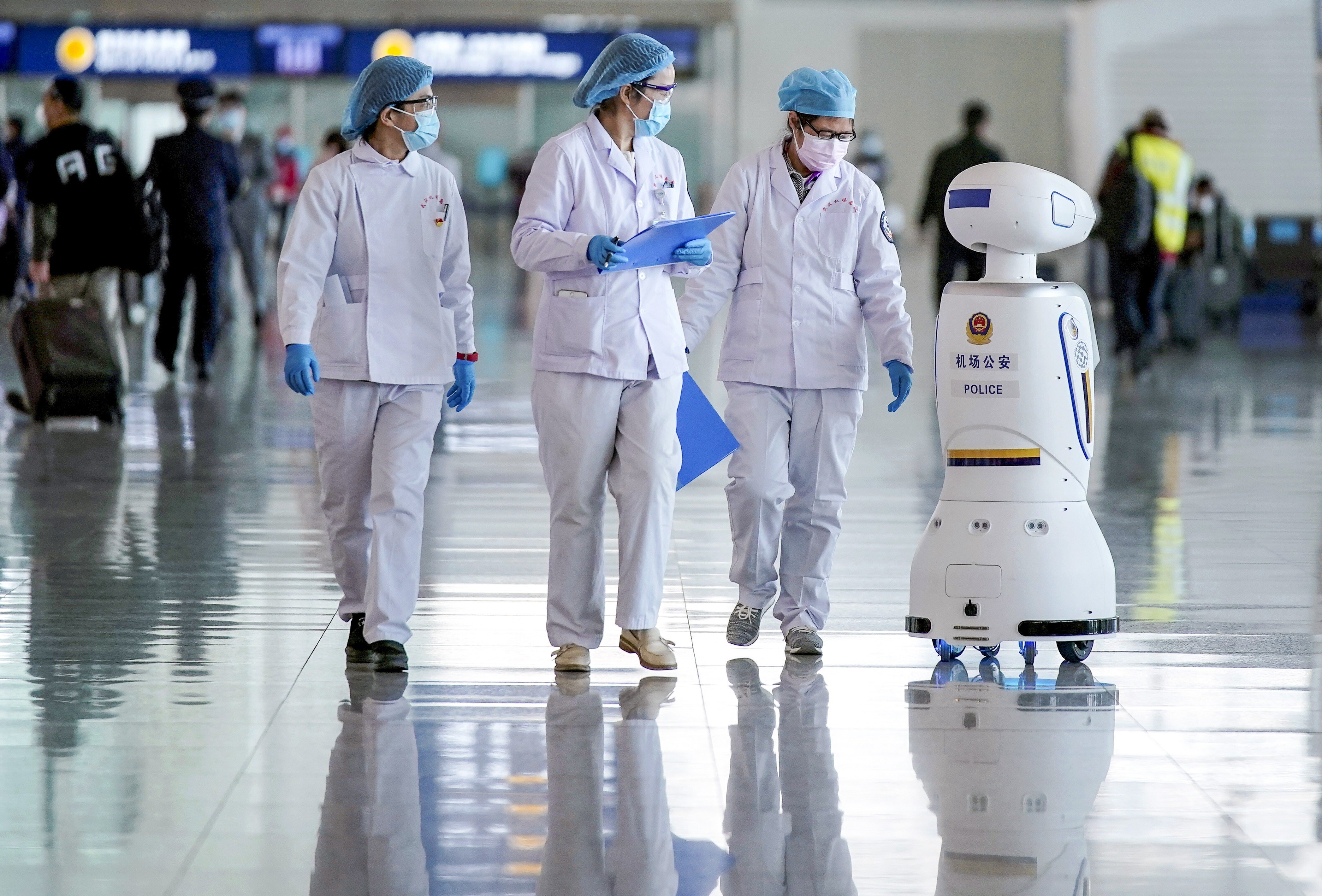Medical workers walk by a police robot at the Wuhan Tianhe International Airport after travel restrictions to leave Wuhan, the capital of Hubei province and China's epicentre of the novel coronavirus disease (COVID-19) outbreak, were lifted, April 8, 2020. Photo: Reuters