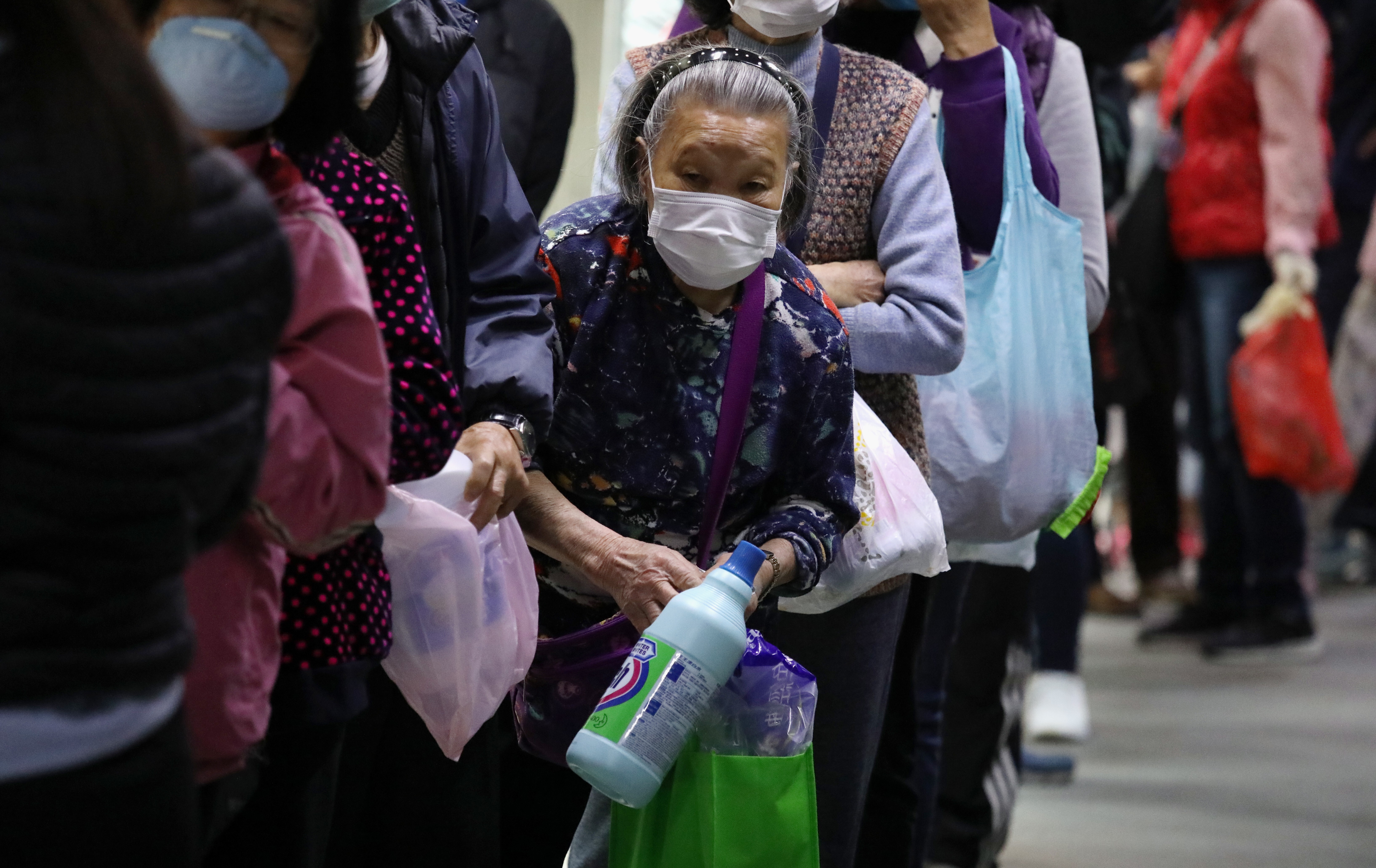 Elderly residents line up to collect 500ml of free bleach being distributed in Kowloon Bay on February 16. Photo: Nora Tam