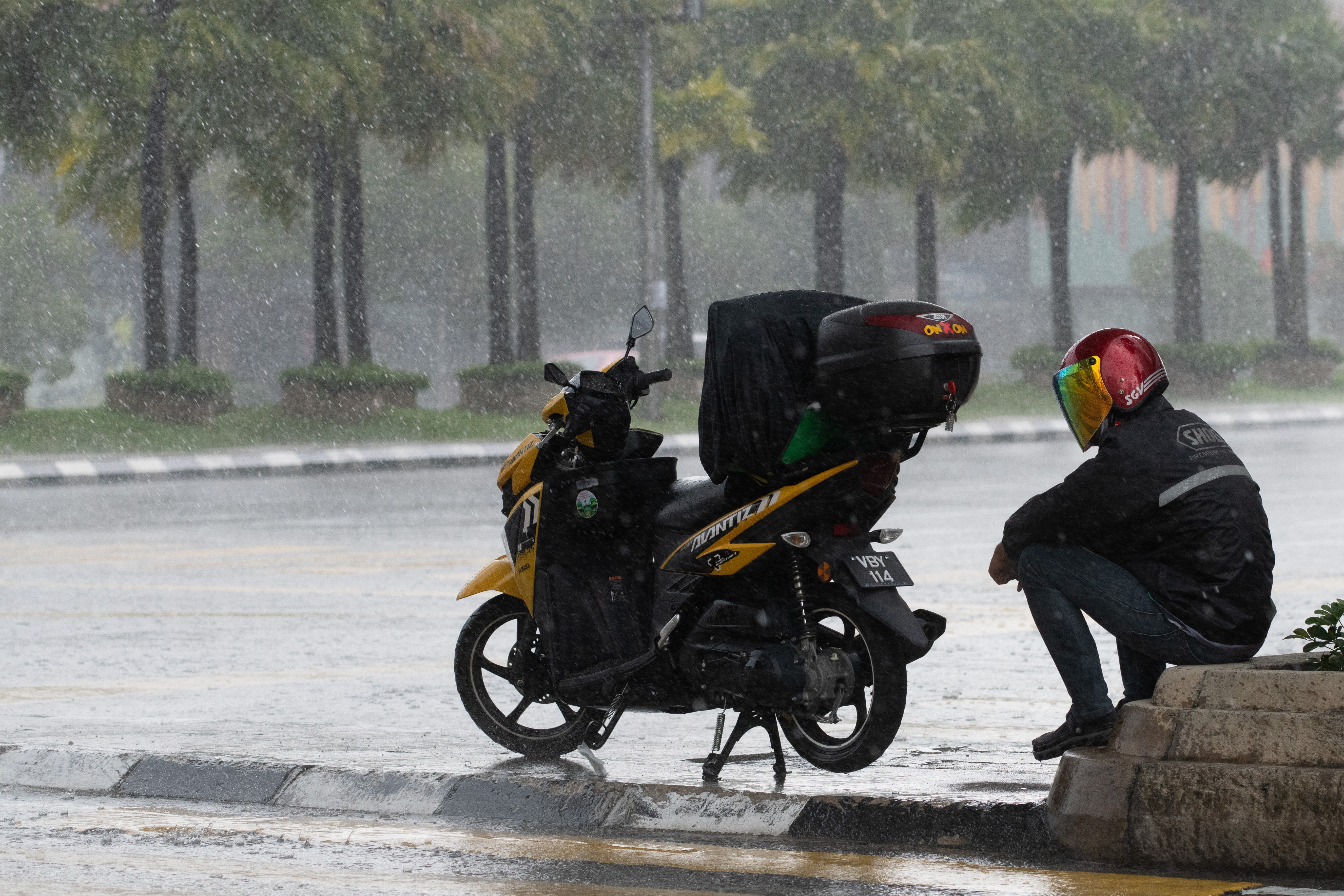 A food delivery rider takes shelter under a bridge while heavy downpour during the Movement Control Order, limiting the activities of people in Malaysia to protect against coronavirus in Kuala Lumpur on April 6. Photo: AFP