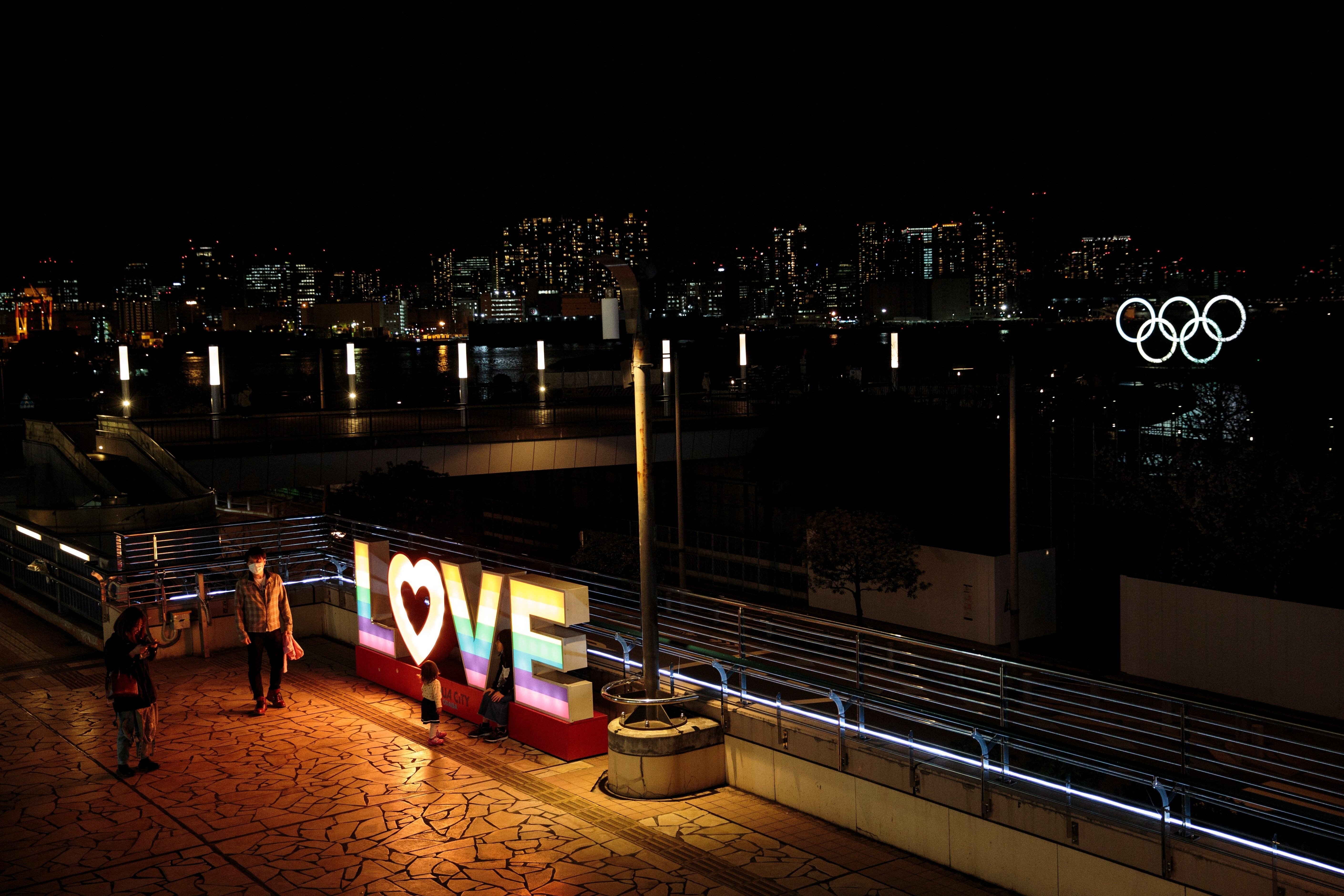 A family stands next to a sign in Tokyo on March 23. Anyone can get sick but everyone can be kinder. Photo: AFP