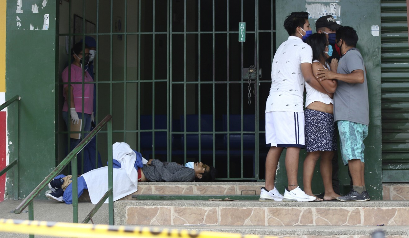 People huddle together as a youth lies at the foot of a locked gate of a doctor's office, in Guayaquil, Ecuador. Photo: AFP