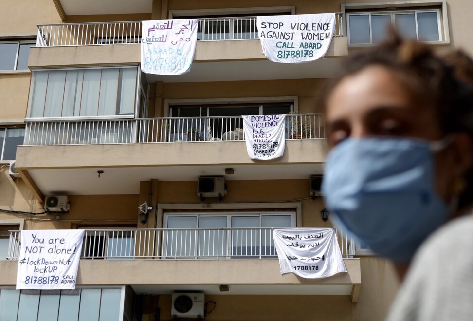 A Lebanese woman walks past a building in Beirut with banners hanging from balconies, carrying messages against domestic violence on April 16. The campaign #LockdownNotLockup was launched by a local group to raise awareness about the issue. Photo: AFP