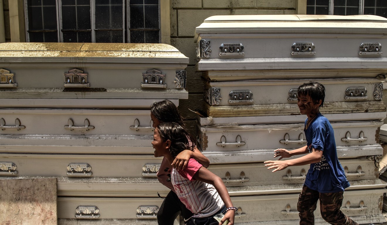 Children run past used caskets at a crematorium facility in Manila. Photo: AFP