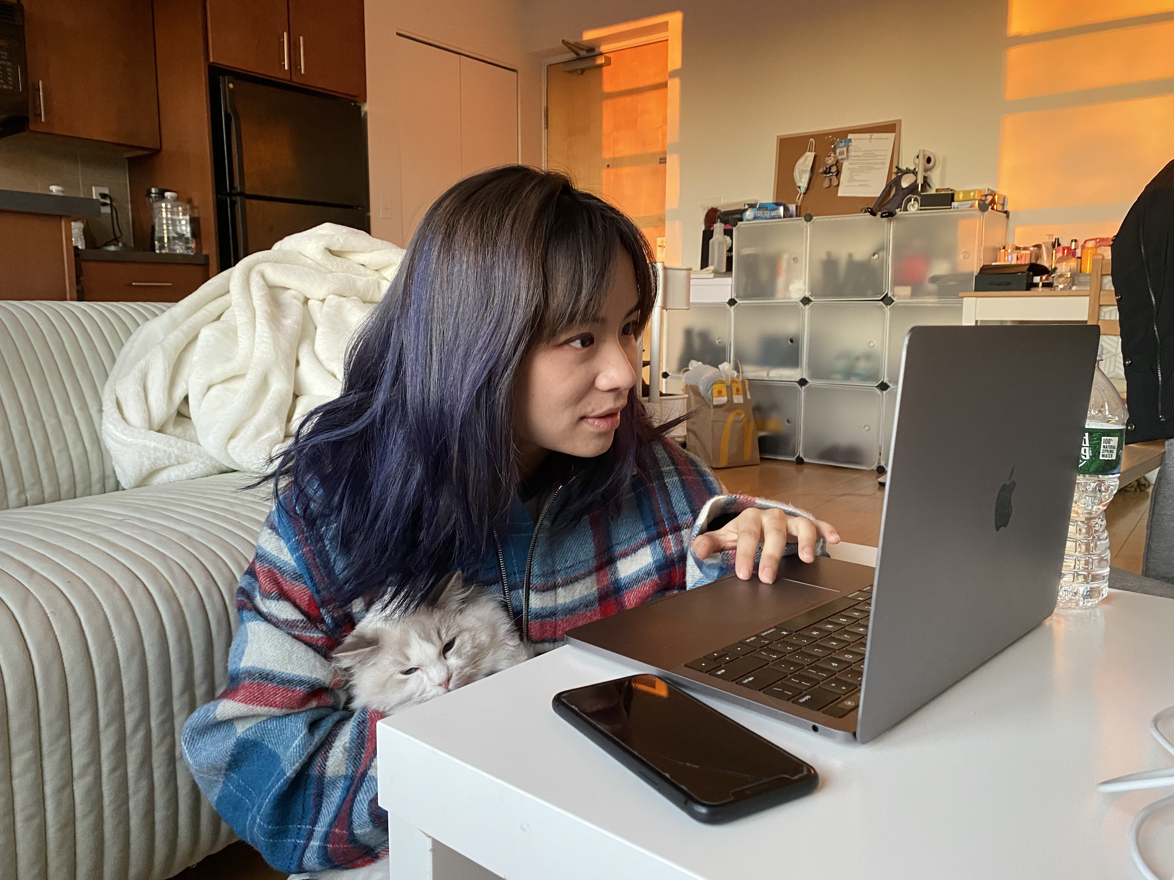 A Chinese student at Boston University works online while cuddling her cat at her home in Boston, Massachusetts, on March 27. While some feel online education is inadequate because of the decreased human interaction, other students find themselves more comfortable interacting with their teachers and peers through screens. Photo: Xinhua