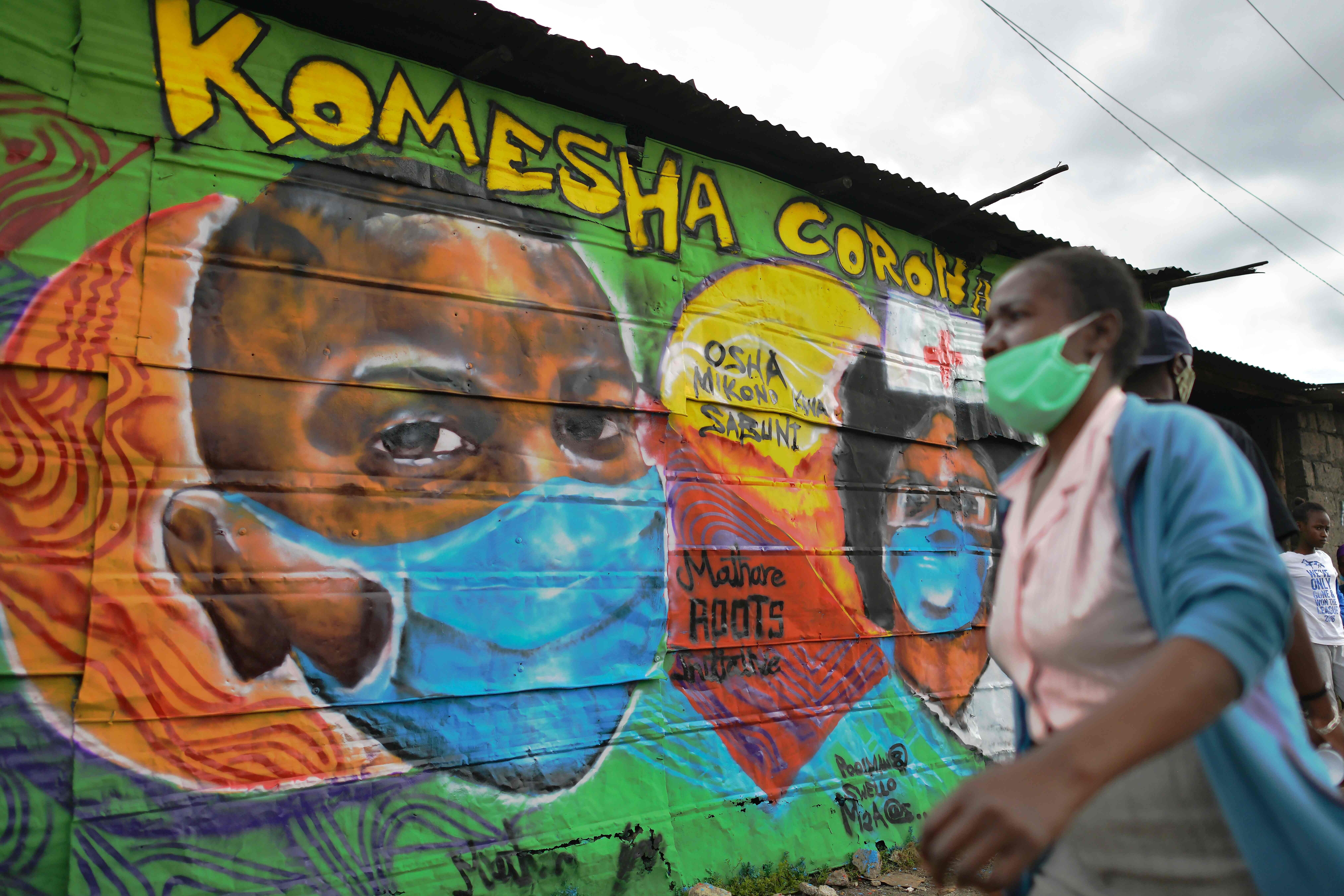 A woman walks past a mural advocating safe practices to curb the spread of Covid-19 at a slum in Nairobi, Kenya, on April 29. Photo: AFP