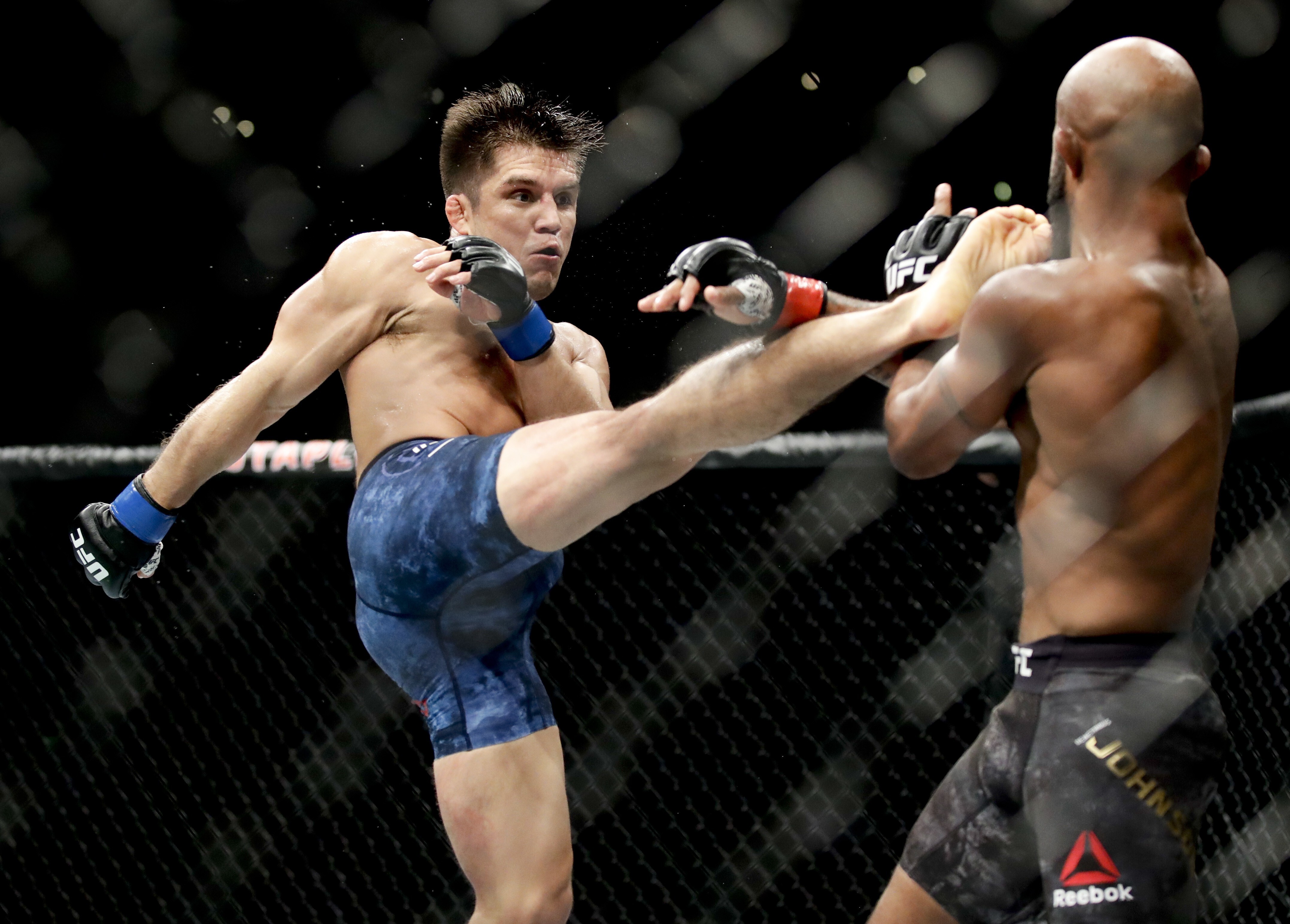 Henry Cejudo kicks Demetrious Johnson during their flyweight title bout at UFC 227. Photo: AP