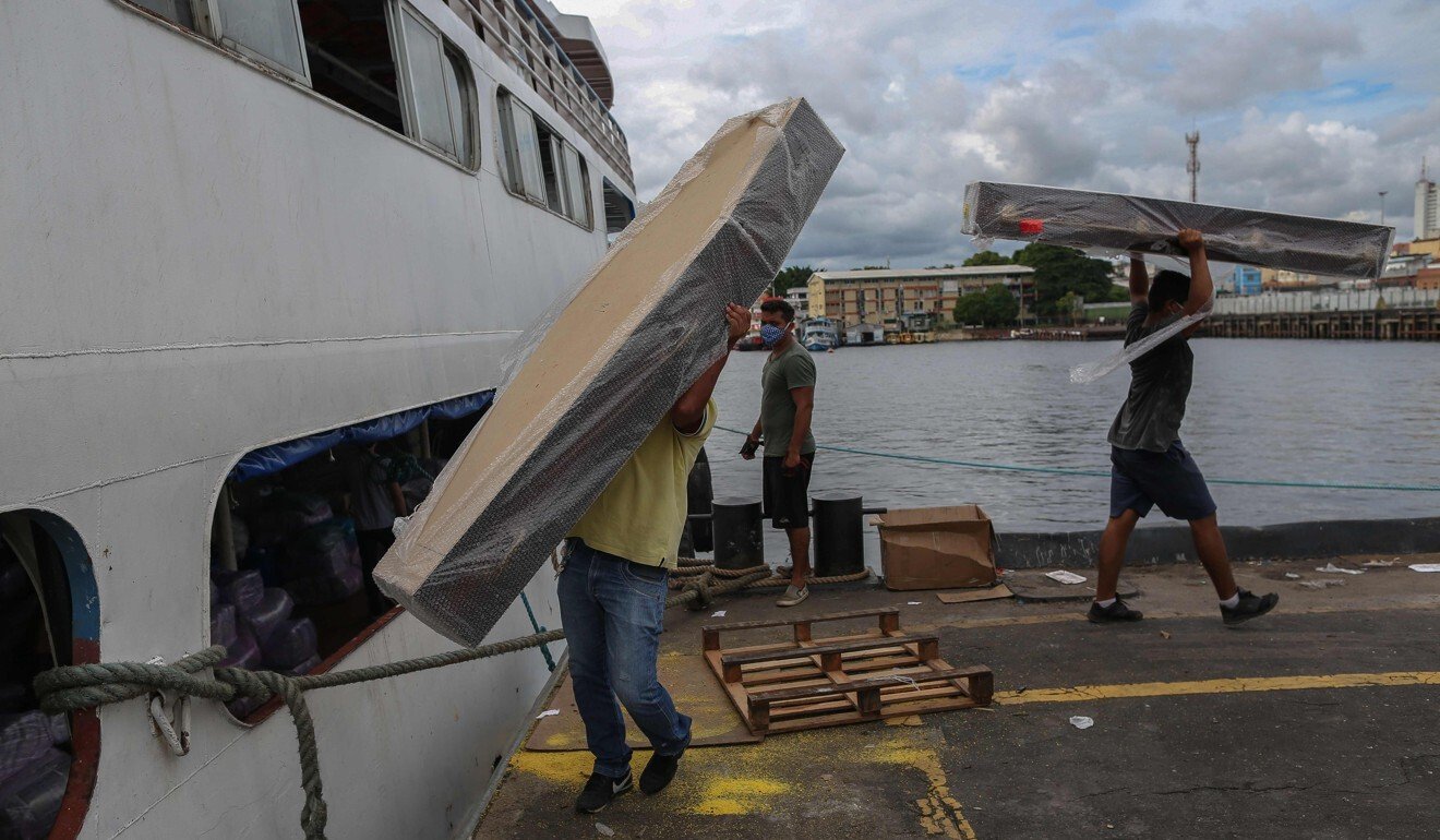 Workers unload coffins from a ship in Manaus Port, Amazonas State, for interning Covid-19 patients. Photo: AFP