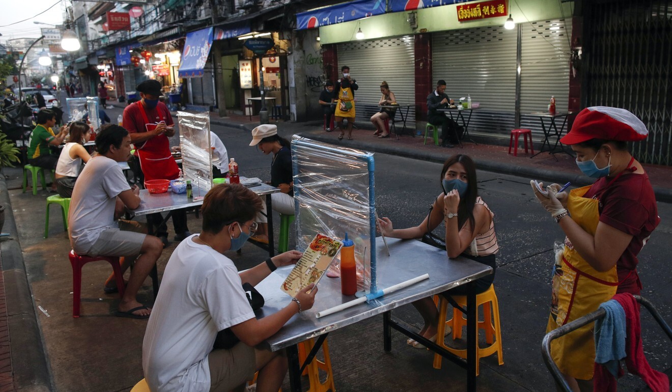 People eat street foods at tables divided with plastic shields in Bangkok on May 12, 2020. Photo: EPA-EFE