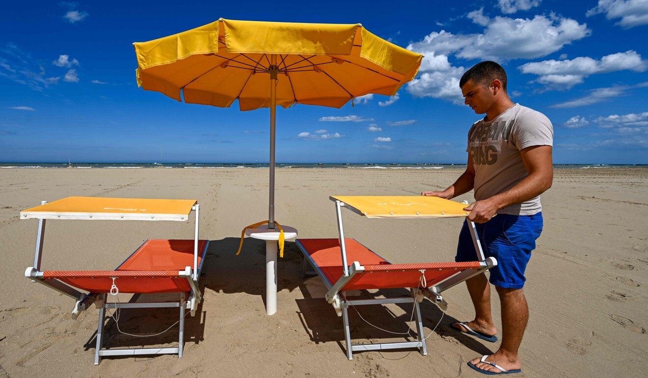 Beach manager Ramon Diego Gargiulo shows the positioning of sunbeds and a sunshade as part of safety precautions for customers at the seafront of Cesenatico in northeastern Italy during the coming summer season. Photo: AFP