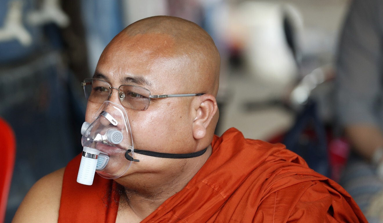 A Buddhist monk wears a face mask while donating food. Photo: EPA