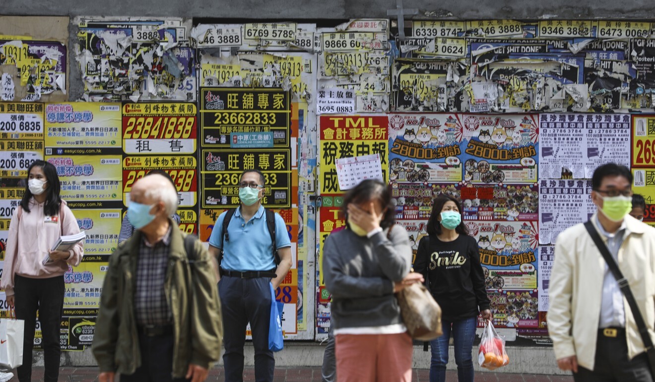People wear masks with shuttered shops in Causeway Bay behind them. Photo Sam Tsang