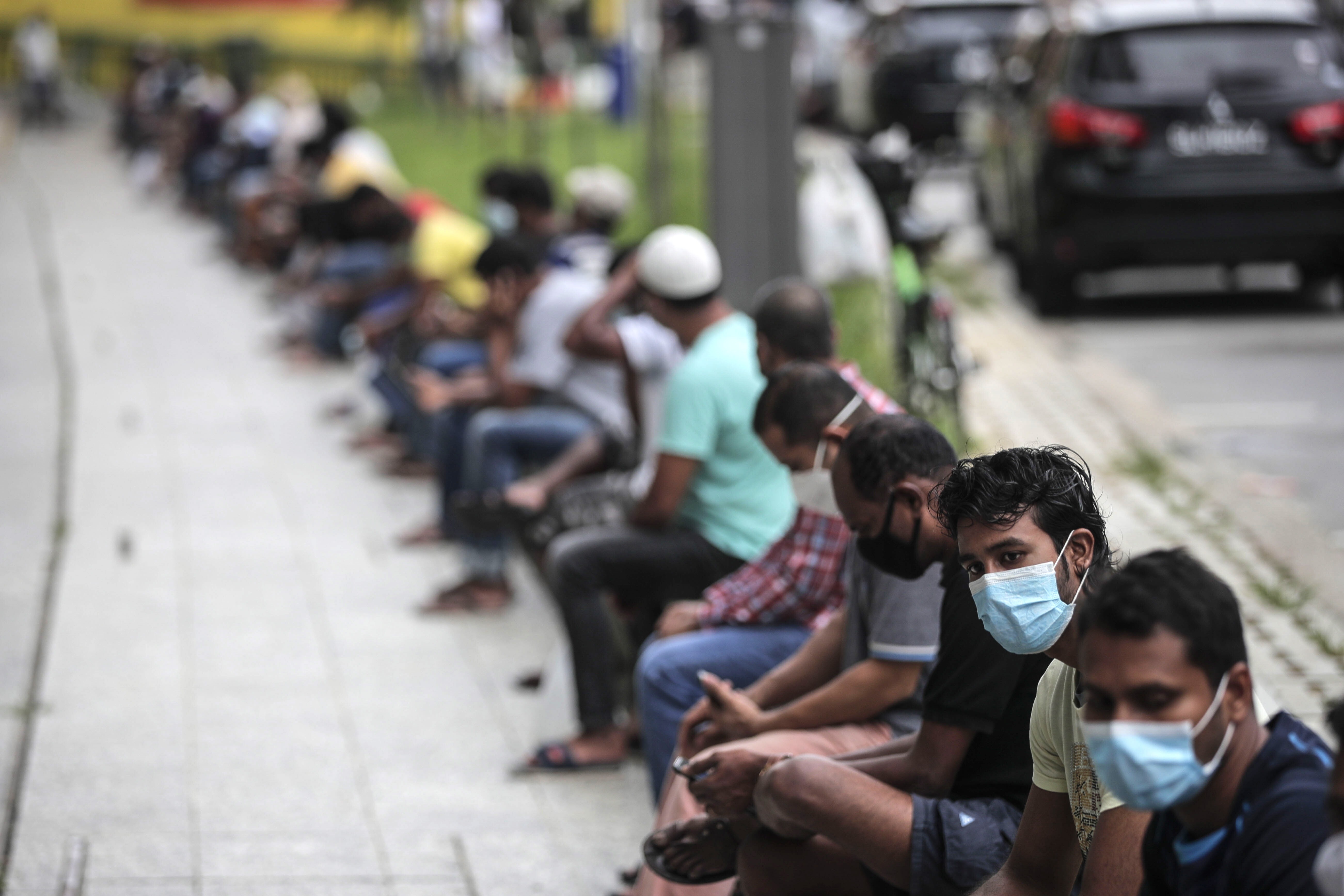 Migrant workers wait in line at a meal distribution point in the Little India district of Singapore, on May 6. A majority of Singapore’s Covid-19 cases are from the foreign worker community, who live in crowded dormitories. Photo: EPA-EFE