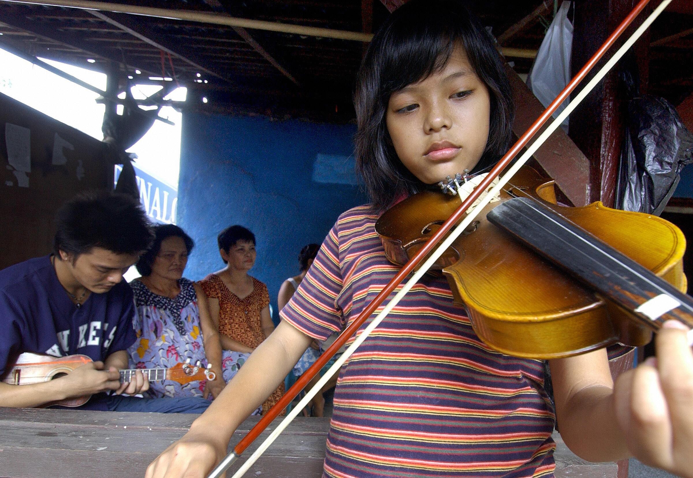 Milton Augustino Michiels and his niece Citra Augusta Margriette (front) play kroncong music at home in Kampung Tugu, Jakarta. A tour company that usually runs guided tours of the urban village has launched a virtual tour of it, and other places of interest in the Indonesian capital, amid the coronavirus pandemic that has halted international travel. Photo: Bay Ismoyo/AFP/Getty Images