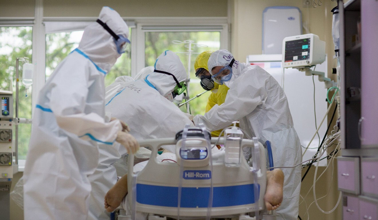 Doctors and medical workers dressed in personal protective equipment turn over an unconscious Covid-19 patient in an intensive care unit in Moscow. Photo: Bloomberg