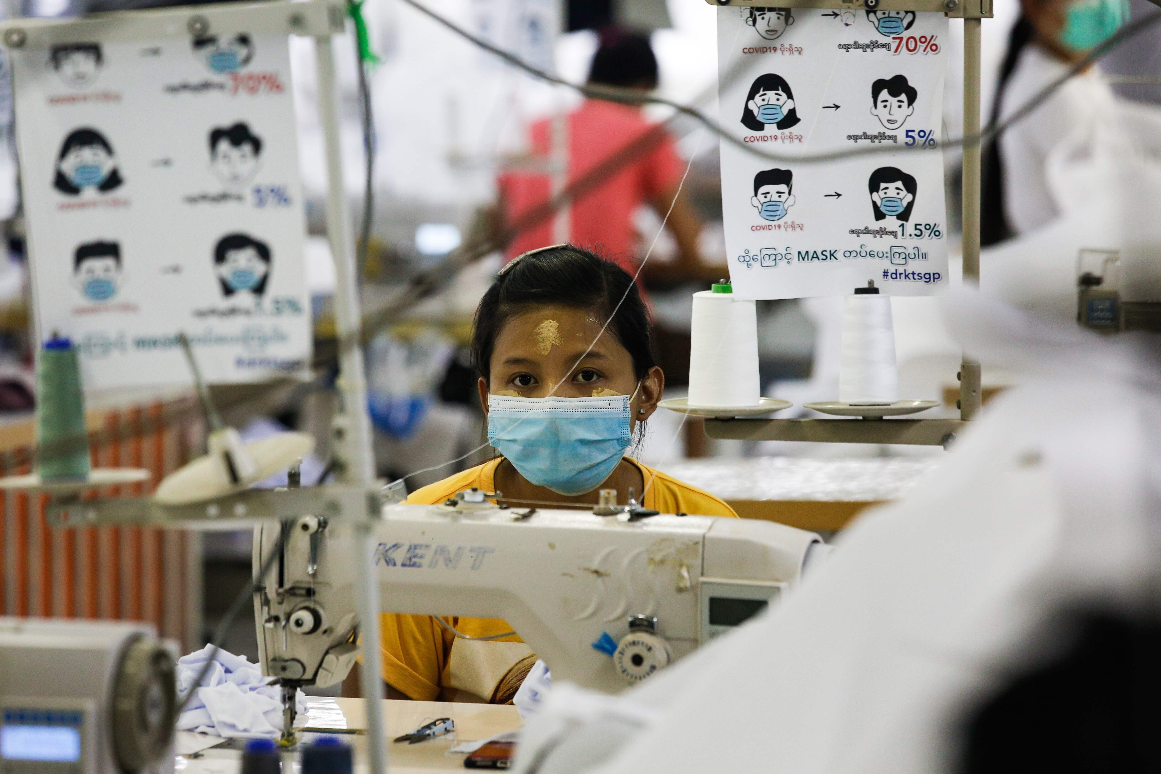 A worker wearing a face mask sews disposable surgical gowns for health workers at a garment factory in Yangon, Myanmar. Photo: AFP
