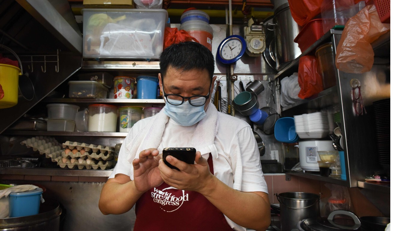 A food stall vendor looks at his phone in Singapore. Photo: AFP