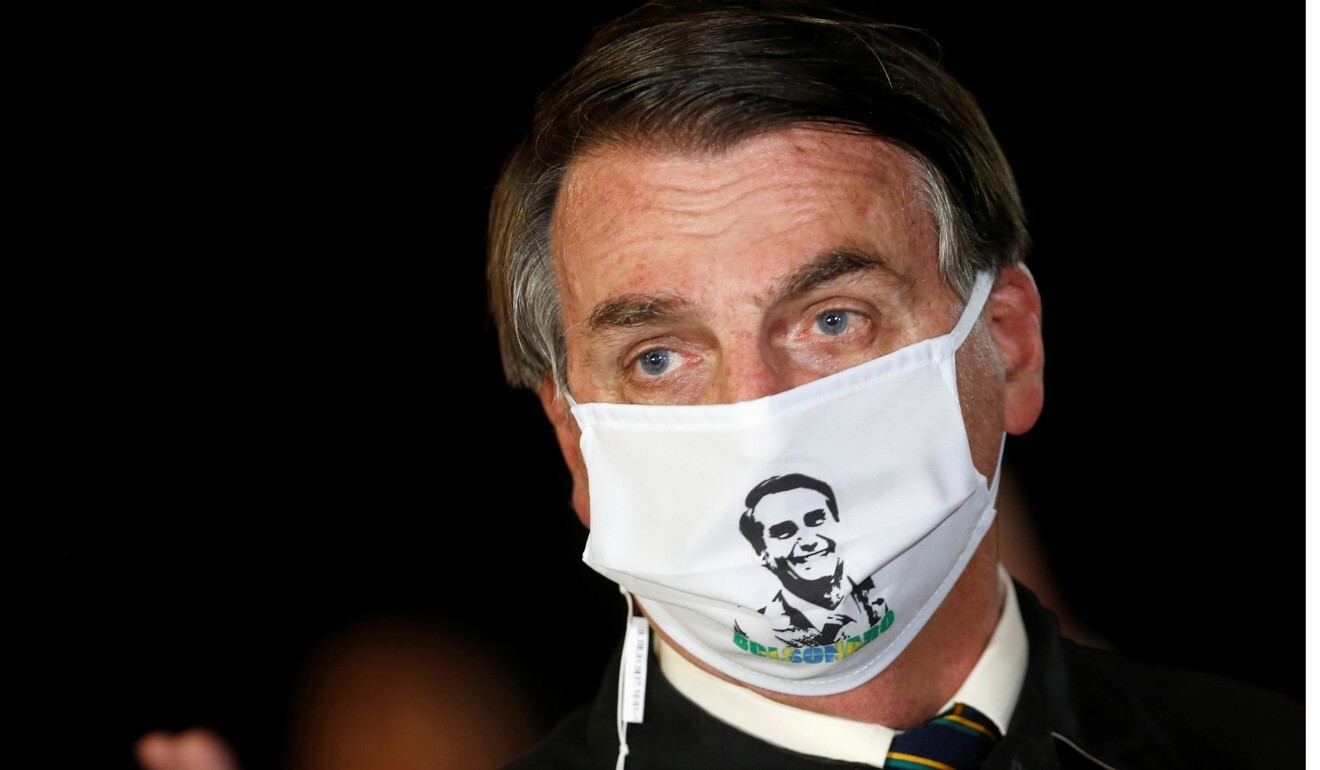 Brazil's President Jair Bolsonaro speaks with journalists while wearing a protective face mask. Photo: Reuters