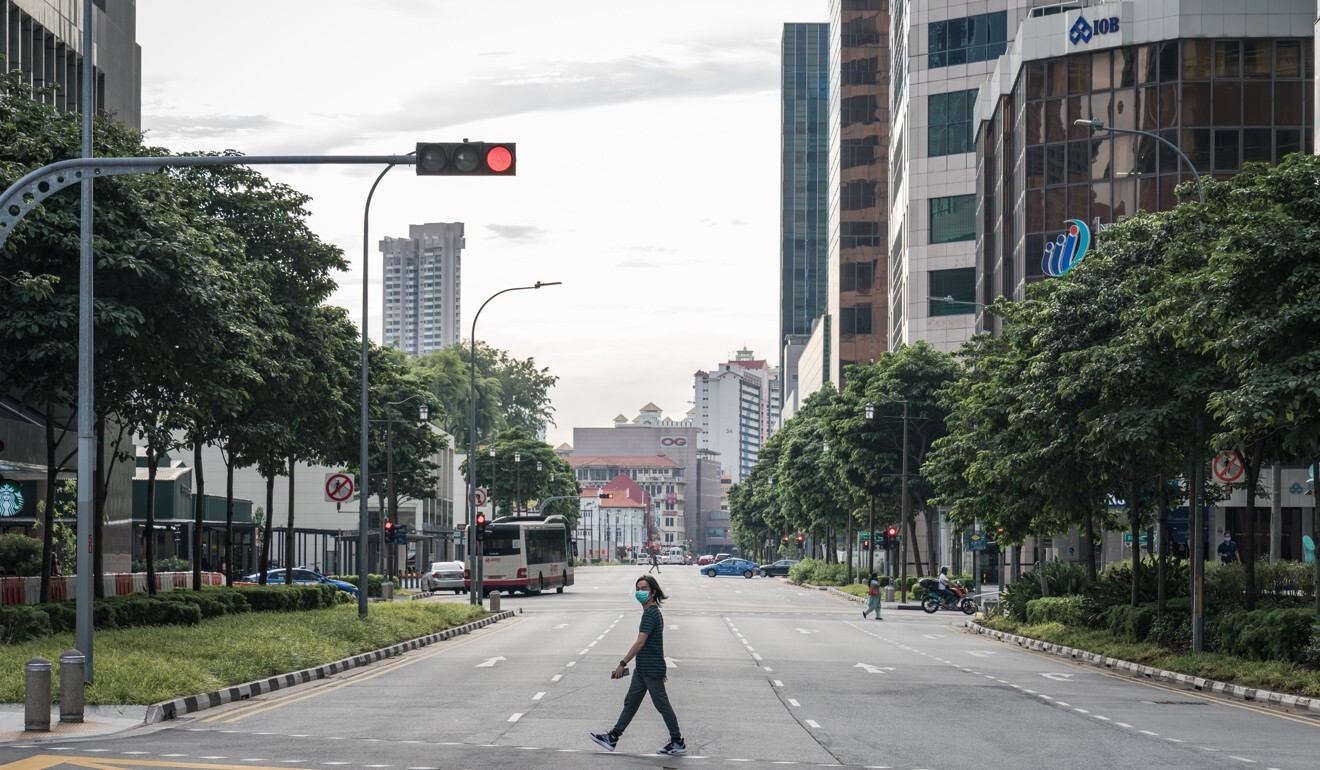 A pedestrian crosses a street in Singapore’s deserted central business district. Photo: Bloomberg