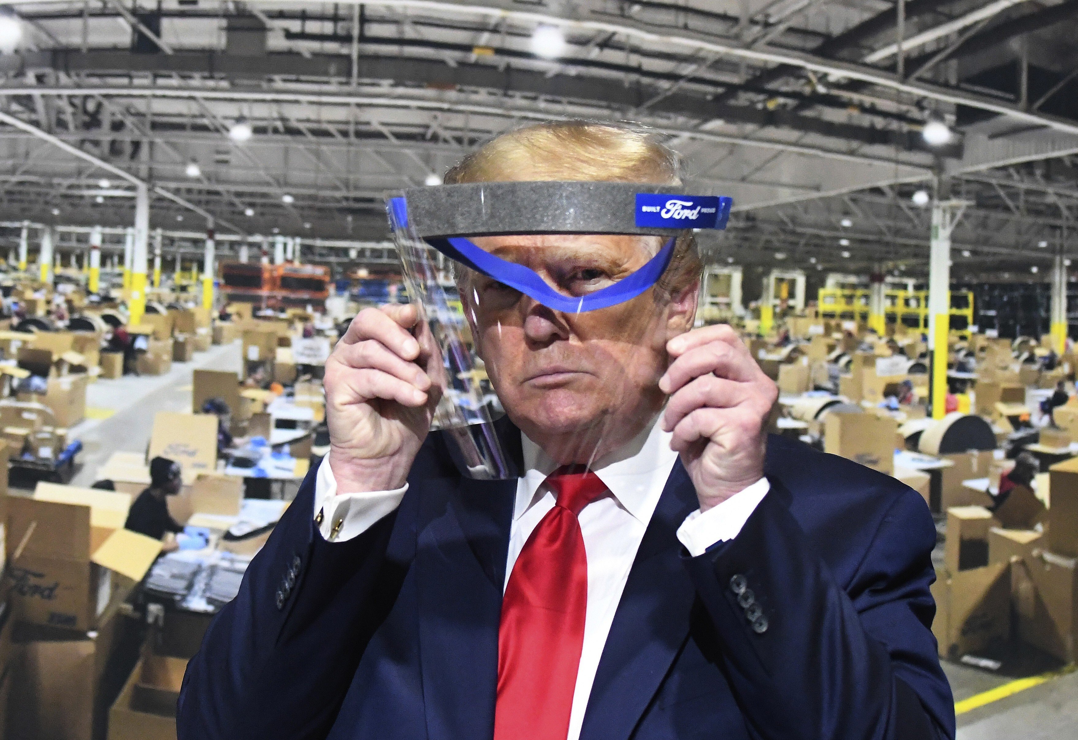US President Donald Trump looks through a face shield, in front of a poster showing the manufacturing of the shields, while touring Ford's Rawsonville Components Plant in Ypsilanti, Michigan, on May 21. Photo: AP