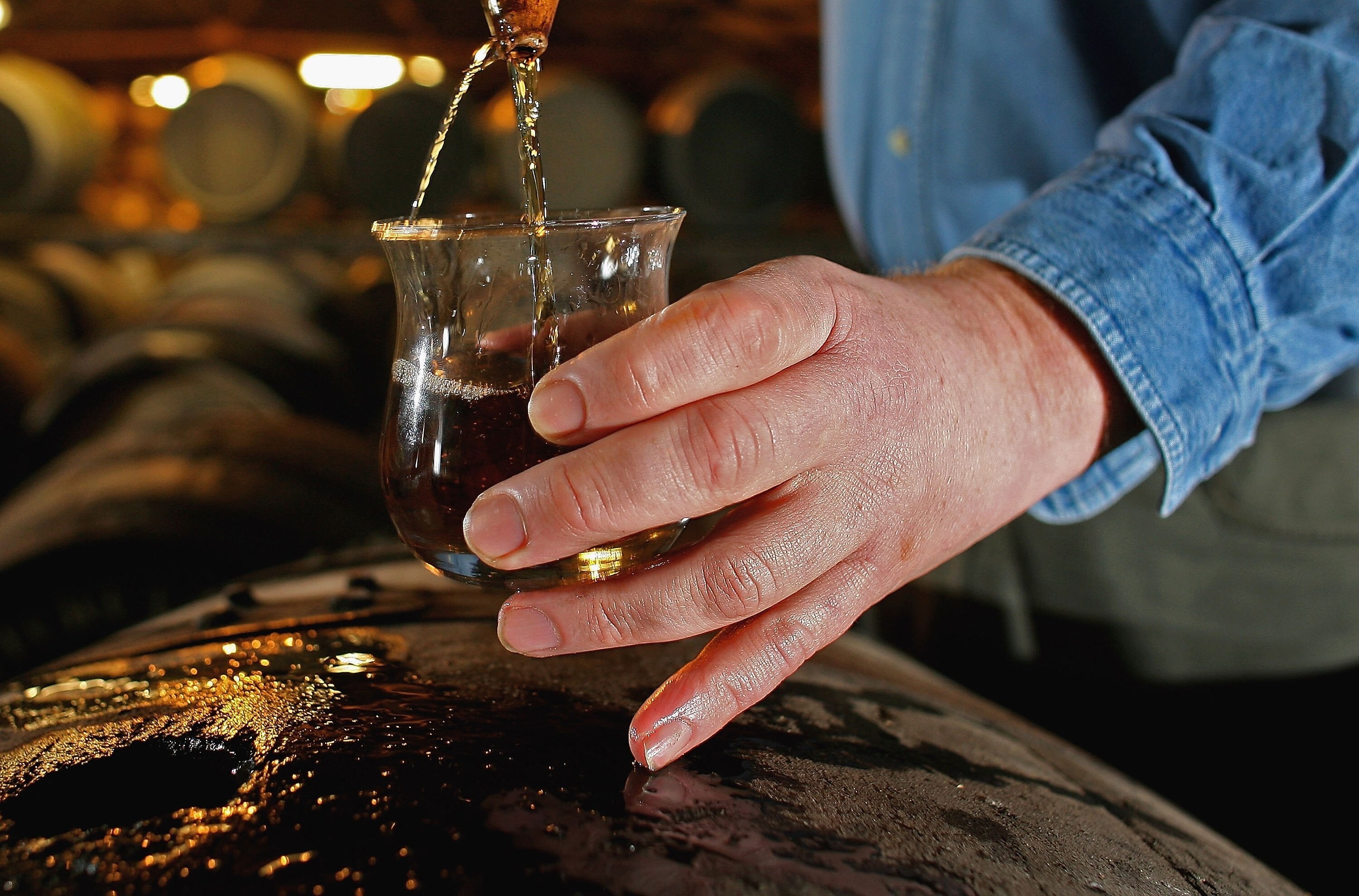 A worker at Bruichladdich distillery takes a whisky sample from a cask. Photo: Getty Images