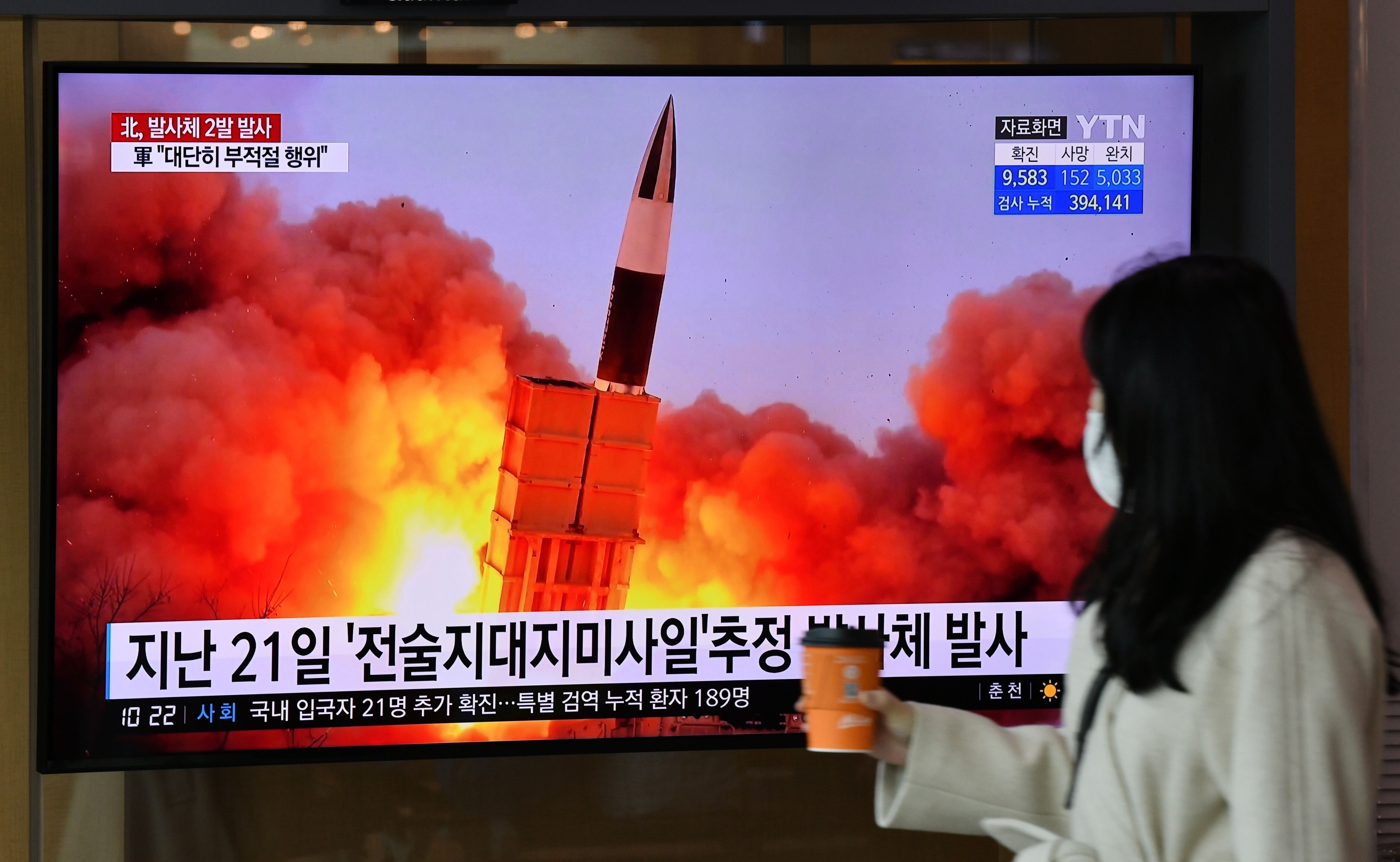 A woman walks past a screen showing file footage of a North Korean missile test at a railway station in Seoul in March. Photo: AFP