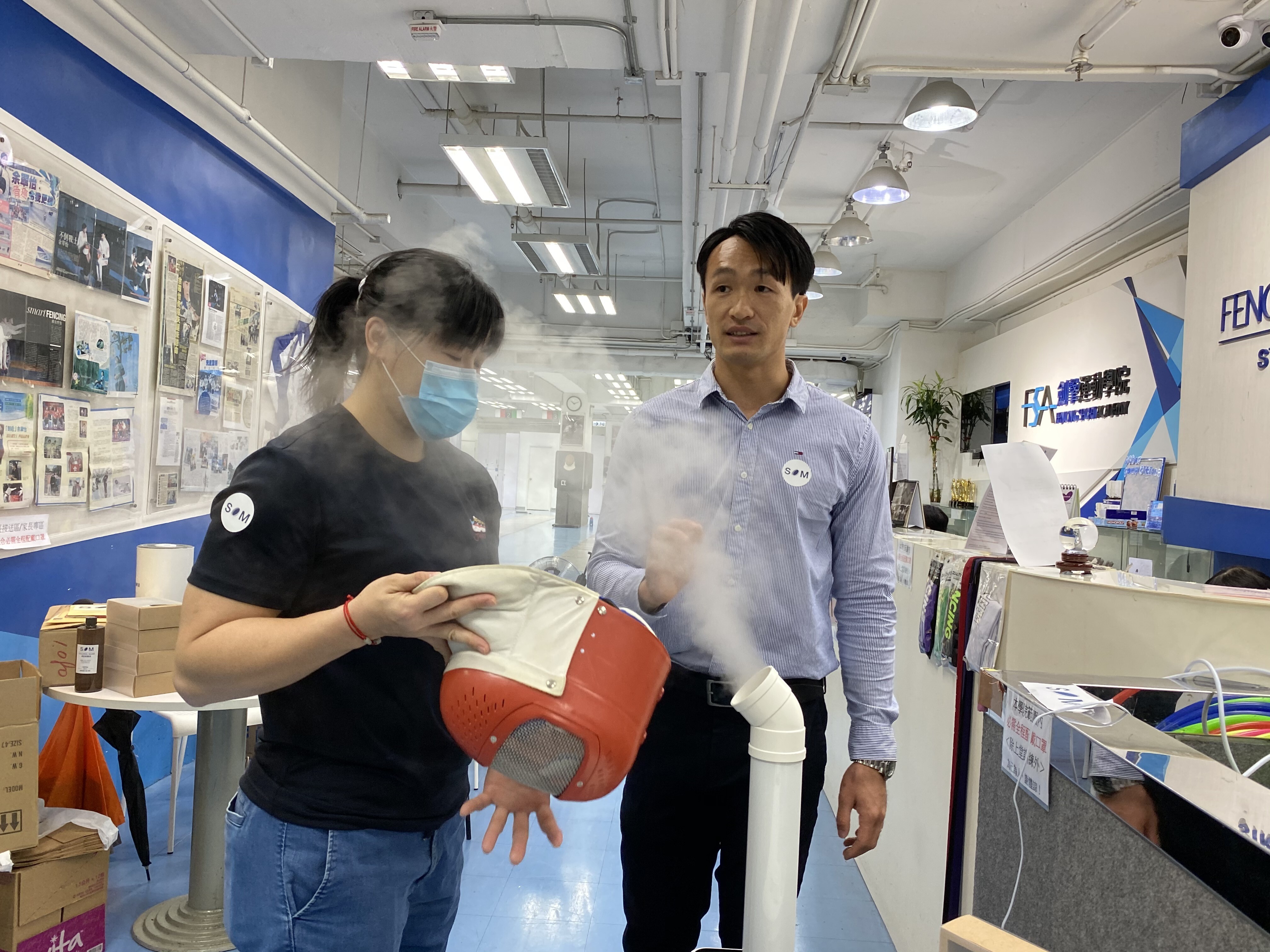 Salom Yiu Kam-shing demonstrates how his disinfection product sterilises a mask with fencer Alison Yu Chui-yee. Photo: Chan Kin-wa