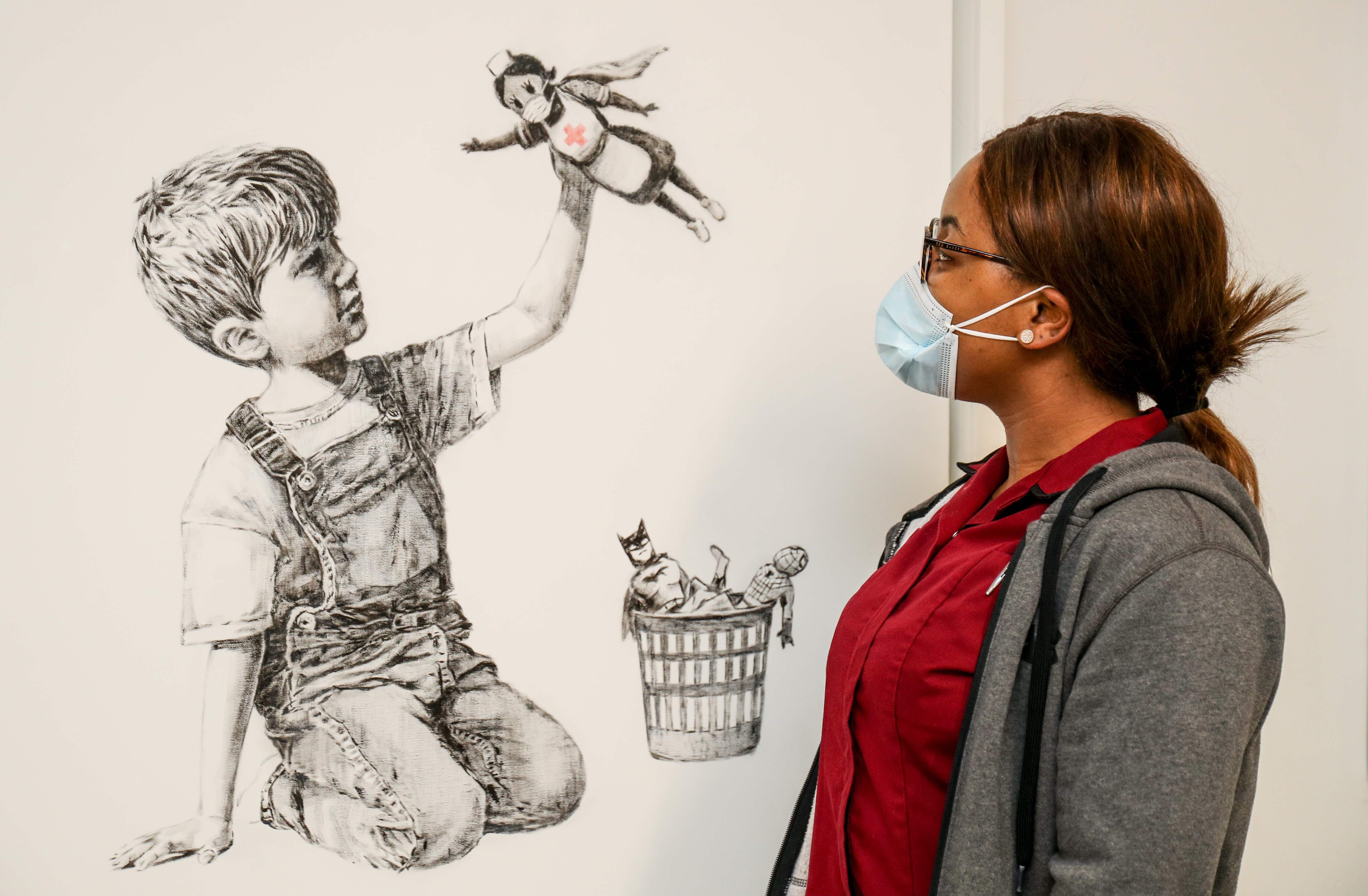 An employee of University Hospital Southampton takes in an artwork by street artist Banksy called Game Changer on May 7. People have shown great willingness to make sacrifices for the sake of health care and other essential workers. Photo: AFP/ University Hospital Southampton