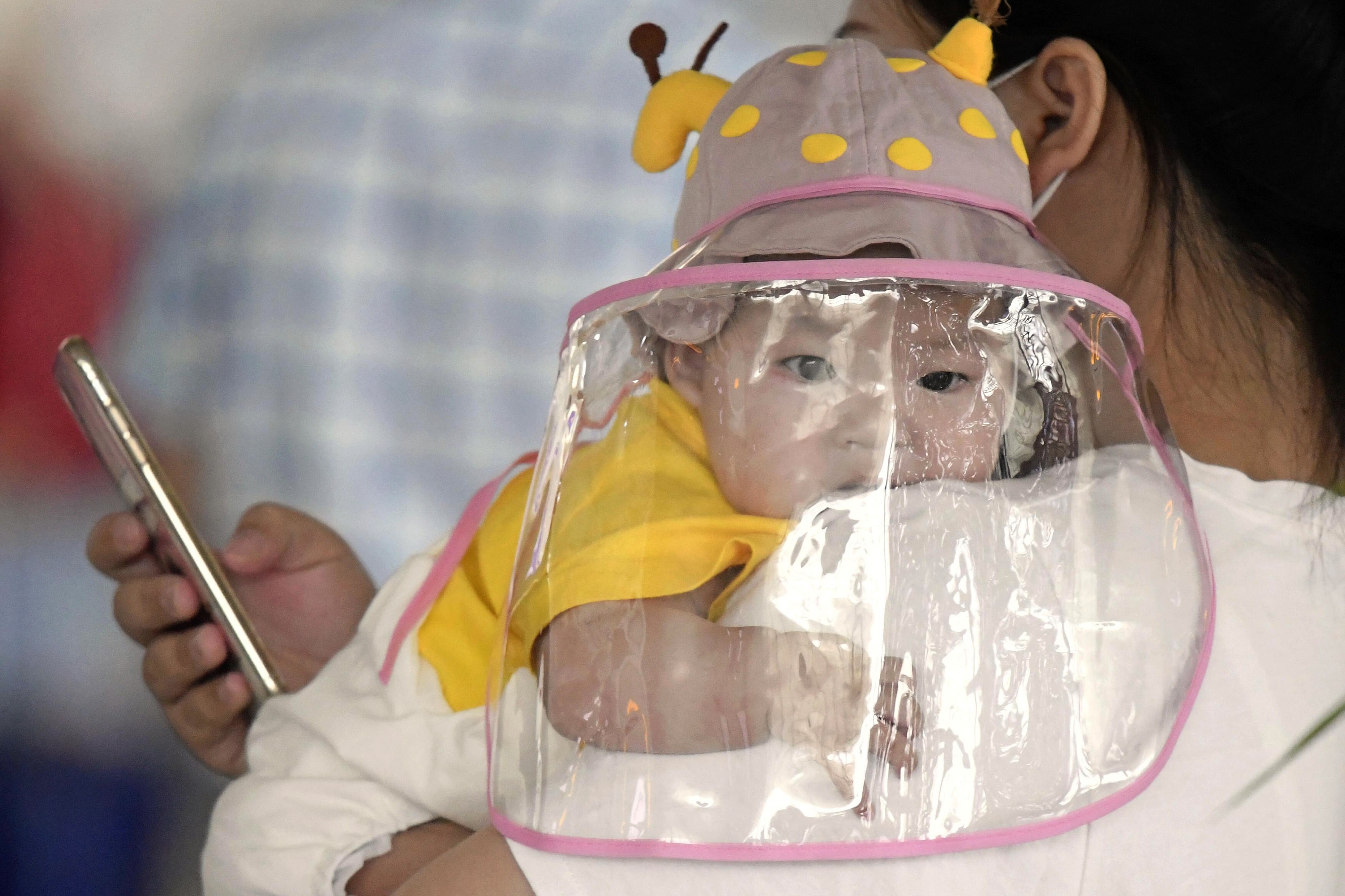 A baby with a face shield waits to board a plane at an airport in Wuhan on May 23. Photo: Kyodo News via AP